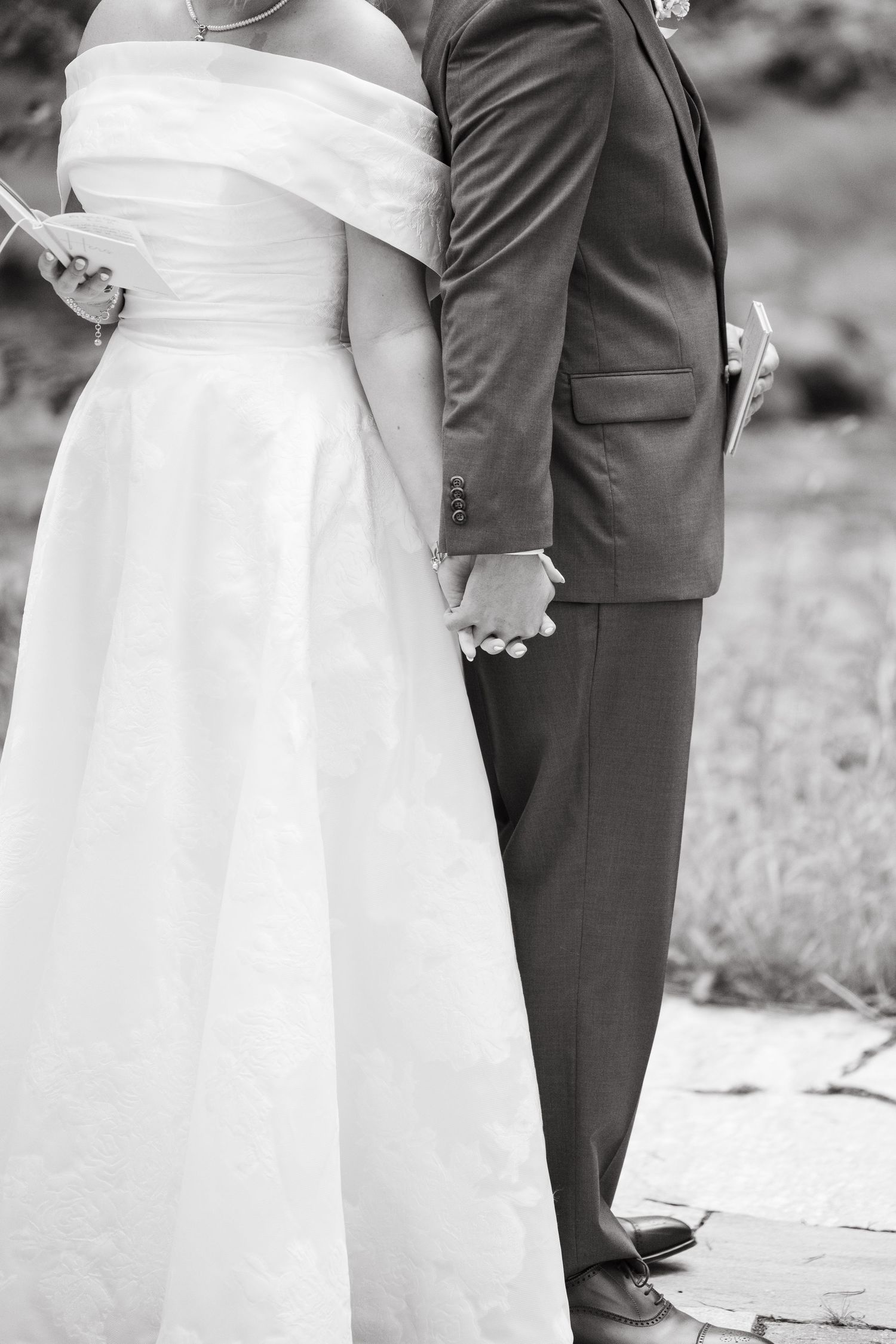 Black and white photo of a couple's feet during a wedding ceremony, showing dress shoes and a white gown during vail wedding.
