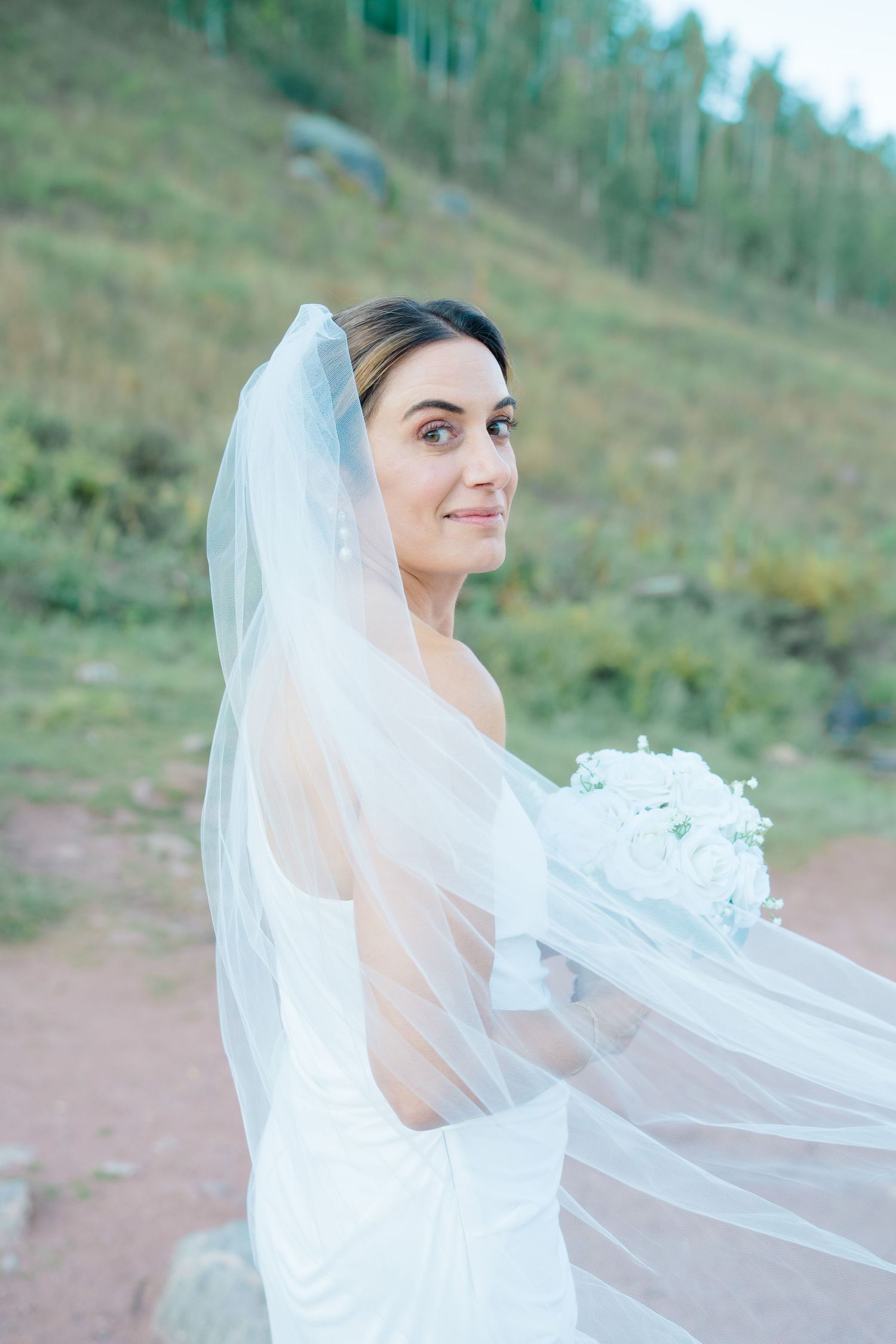 bride looking back at camera at piney river ranch during vail proposal.