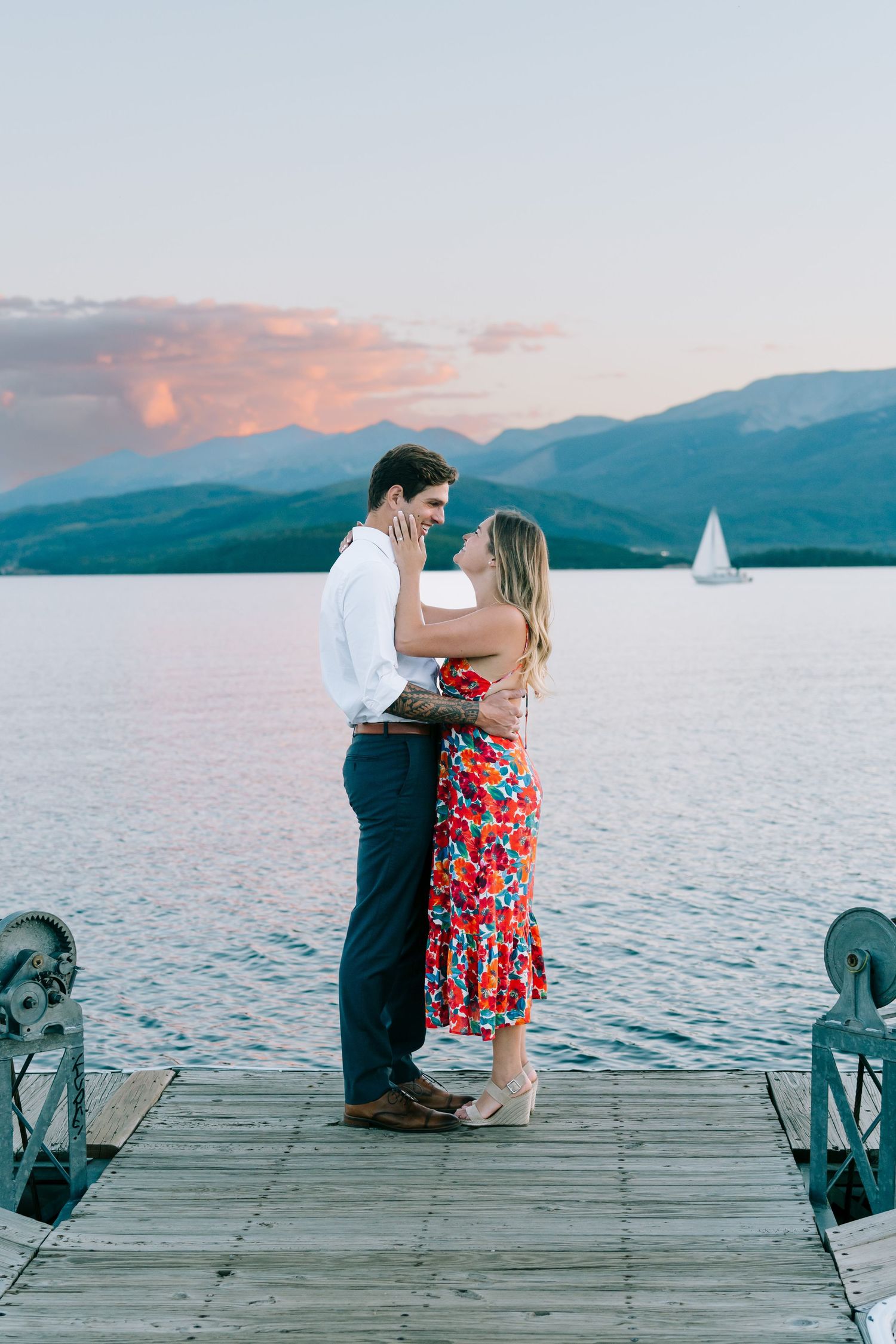 guy and girl kissing by a sail boat