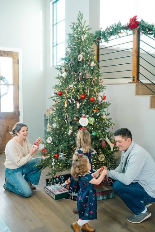 A family decorates a Christmas tree together in a bright, modern living room with large windows - vail family photograph locations
