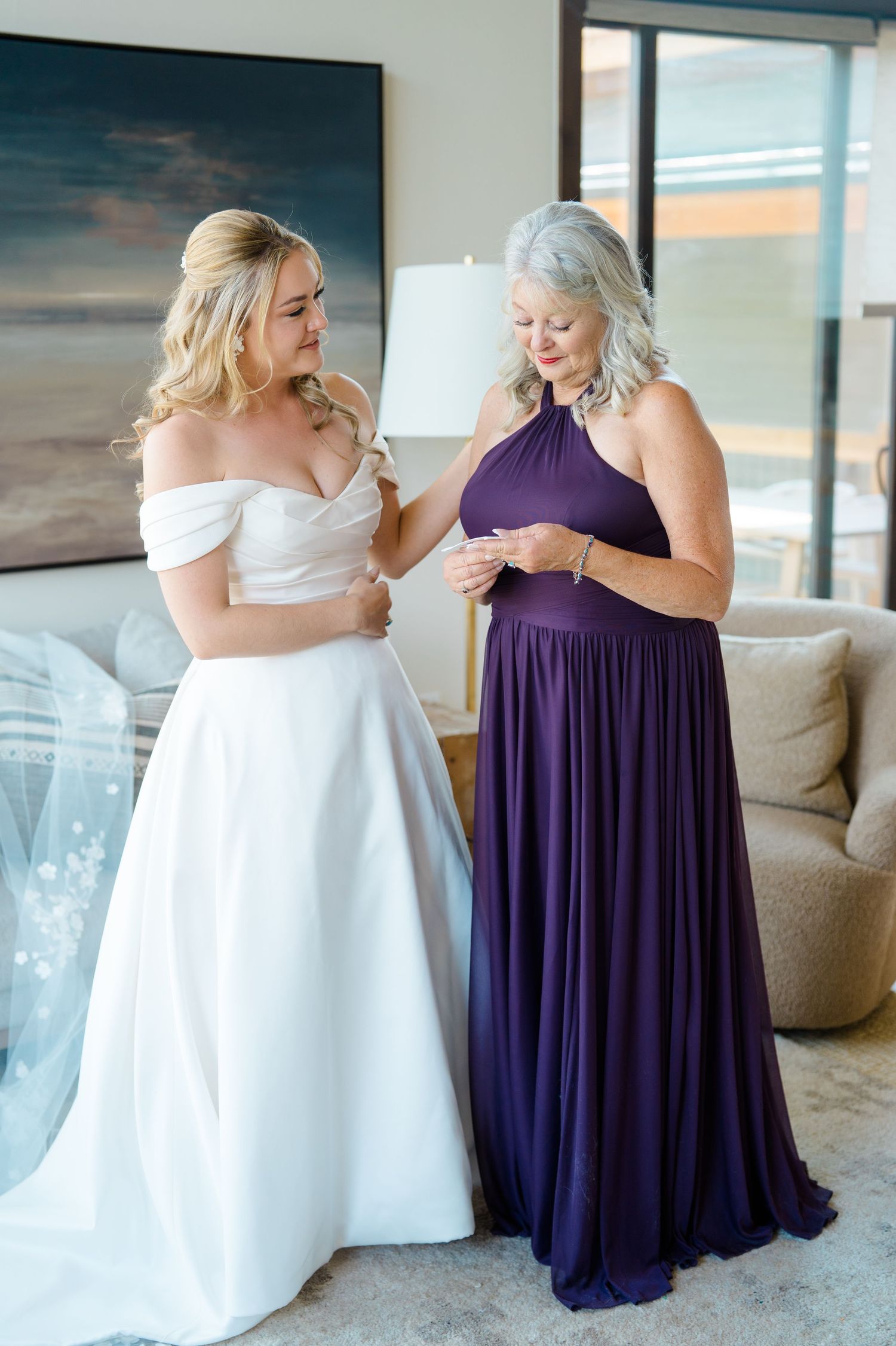 Two people in contrasting white and purple dresses share an emotional embrace in a sunlit room during Breckenridge wedding.