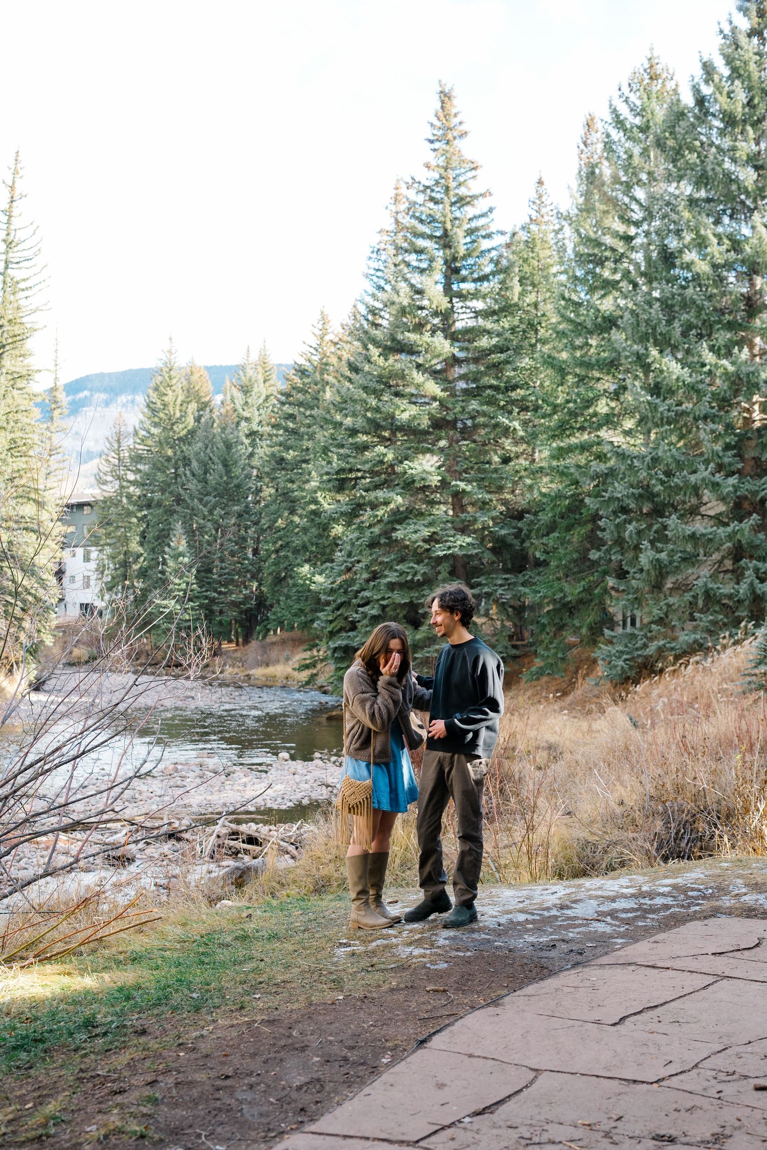 A group of people explore a scenic mountain trail lined with evergreen trees and fallen logs.