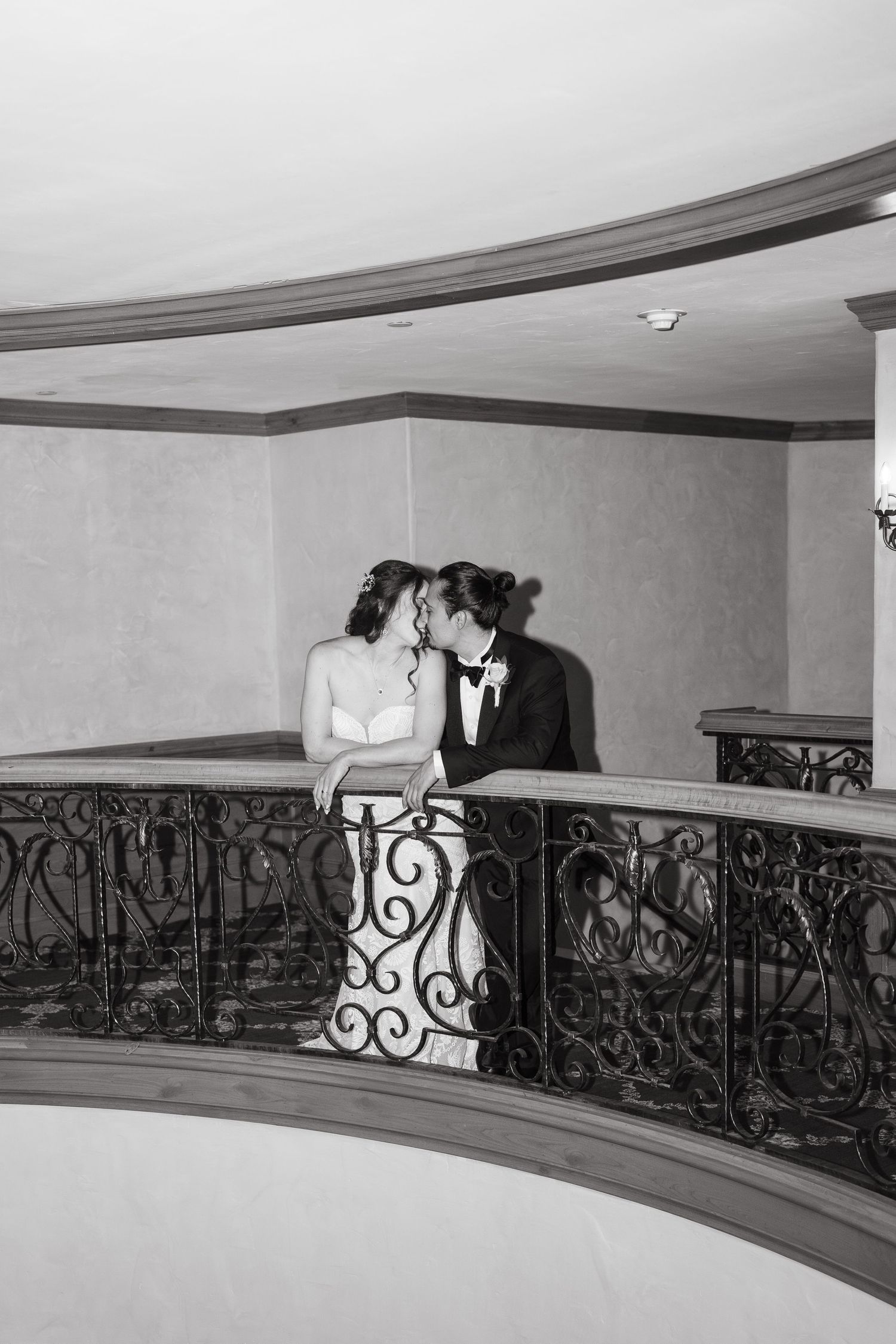 A black and white wedding photo featuring an elegant curved balcony with ornate iron railings at vail wedding.