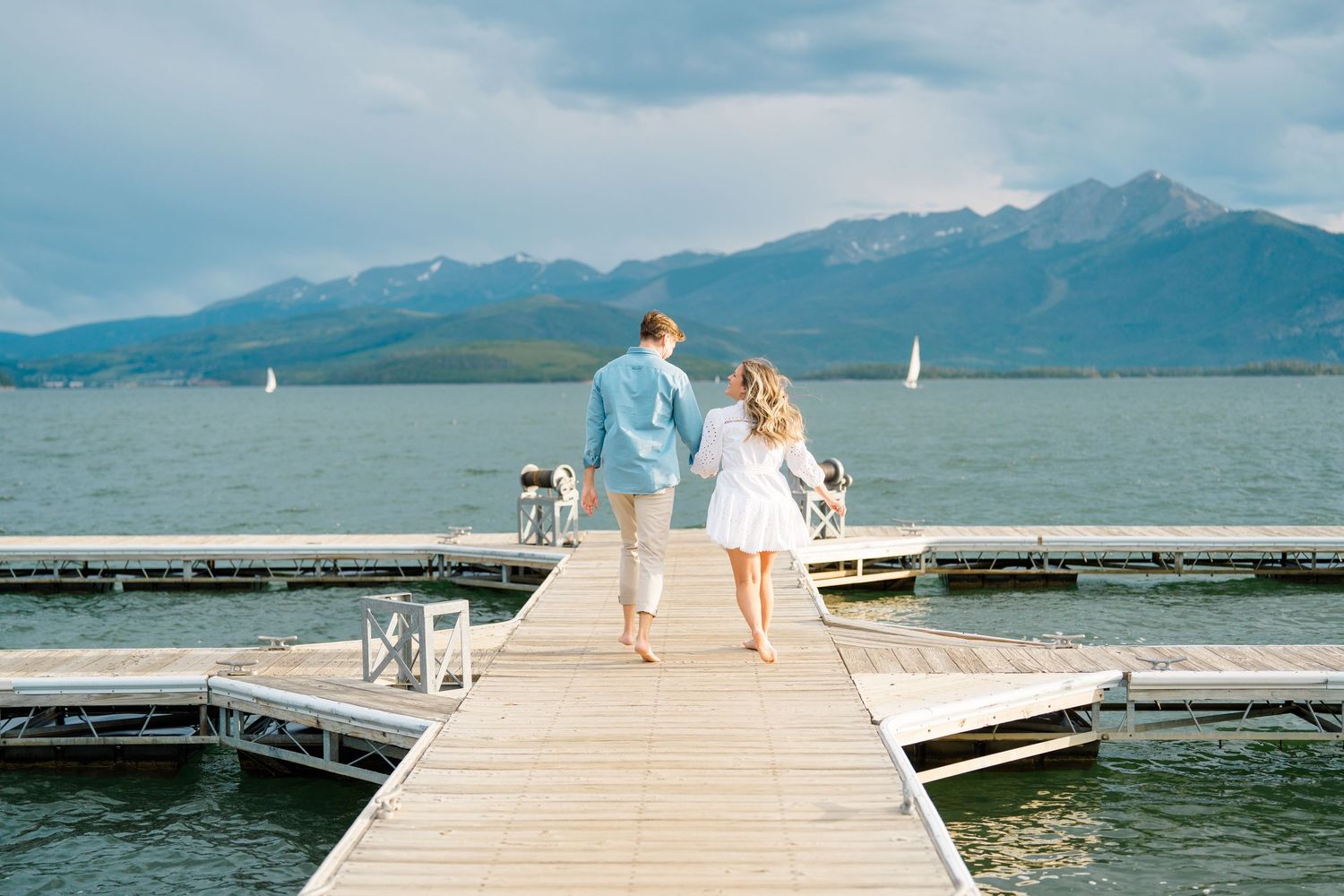 A wooden dock stretches into a scenic mountain lake with turquoise waters and snow-capped peaks in the background at lake dillon.