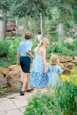 People sit on large rocks in a lush garden setting with greenery and flowers on a sunny summer day - best summer locations for vail photos