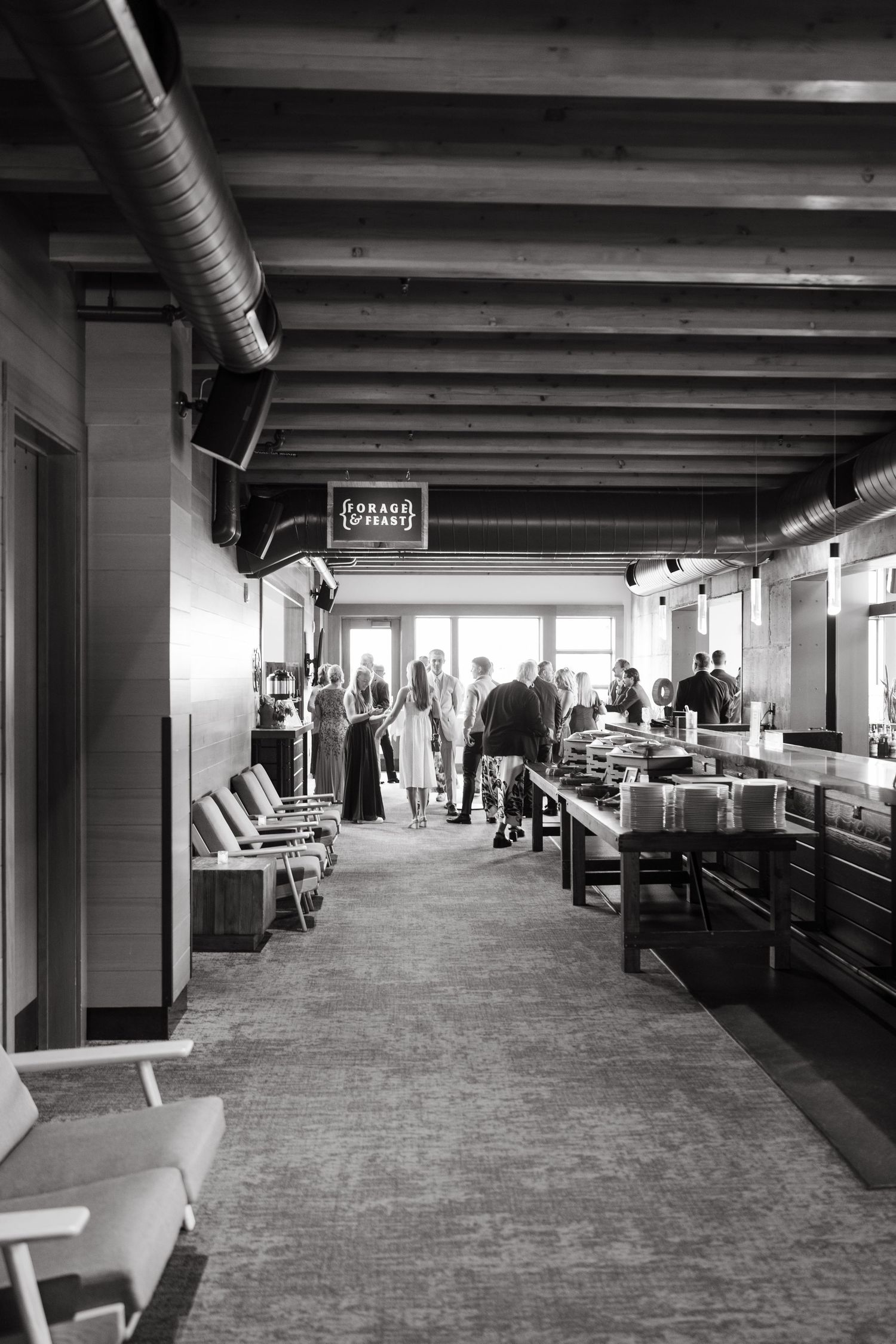 Black and white interior hallway with exposed ceiling beams and people walking through a commercial space at Aerie at Copper Mountain.