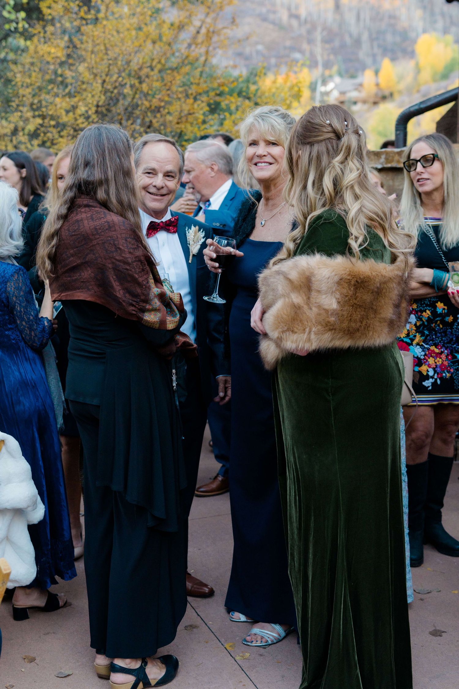 Elegantly dressed guests mingle outdoors at an autumn wedding reception, wearing formal gowns and suits at Donovan Pavillion Vail Wedding.