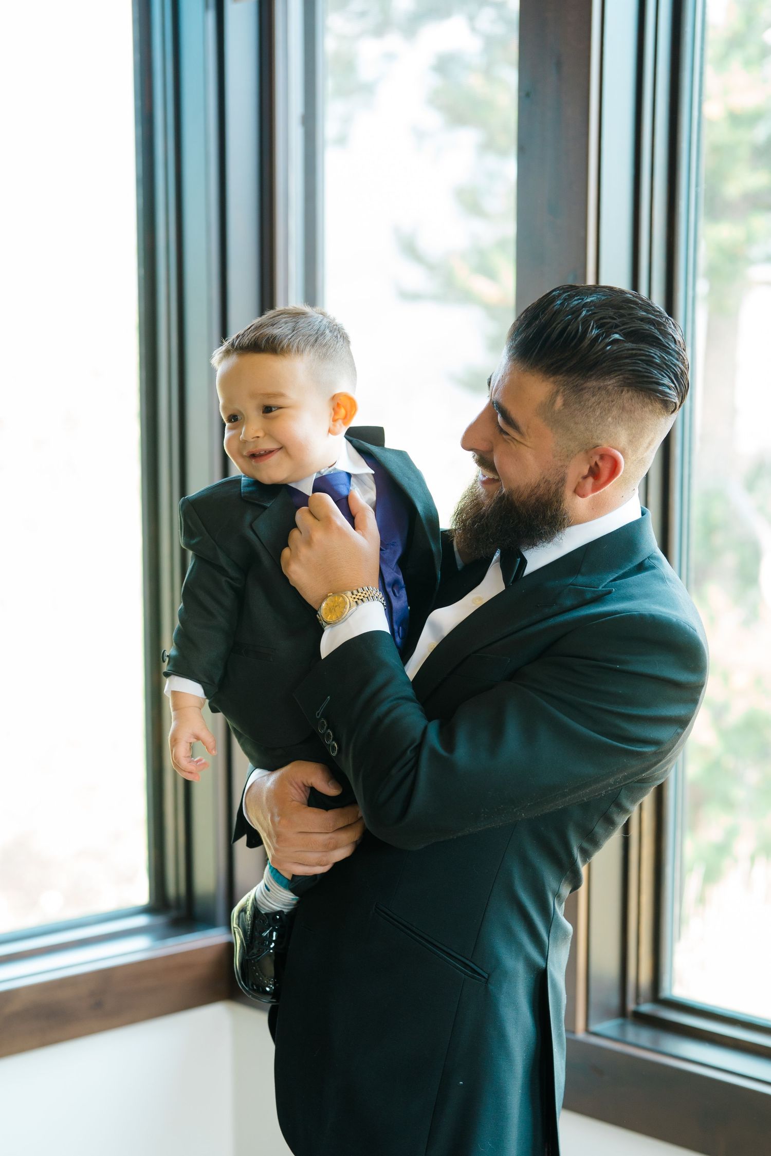 A series of heartwarming moments captured between two people in formal attire by large windows.