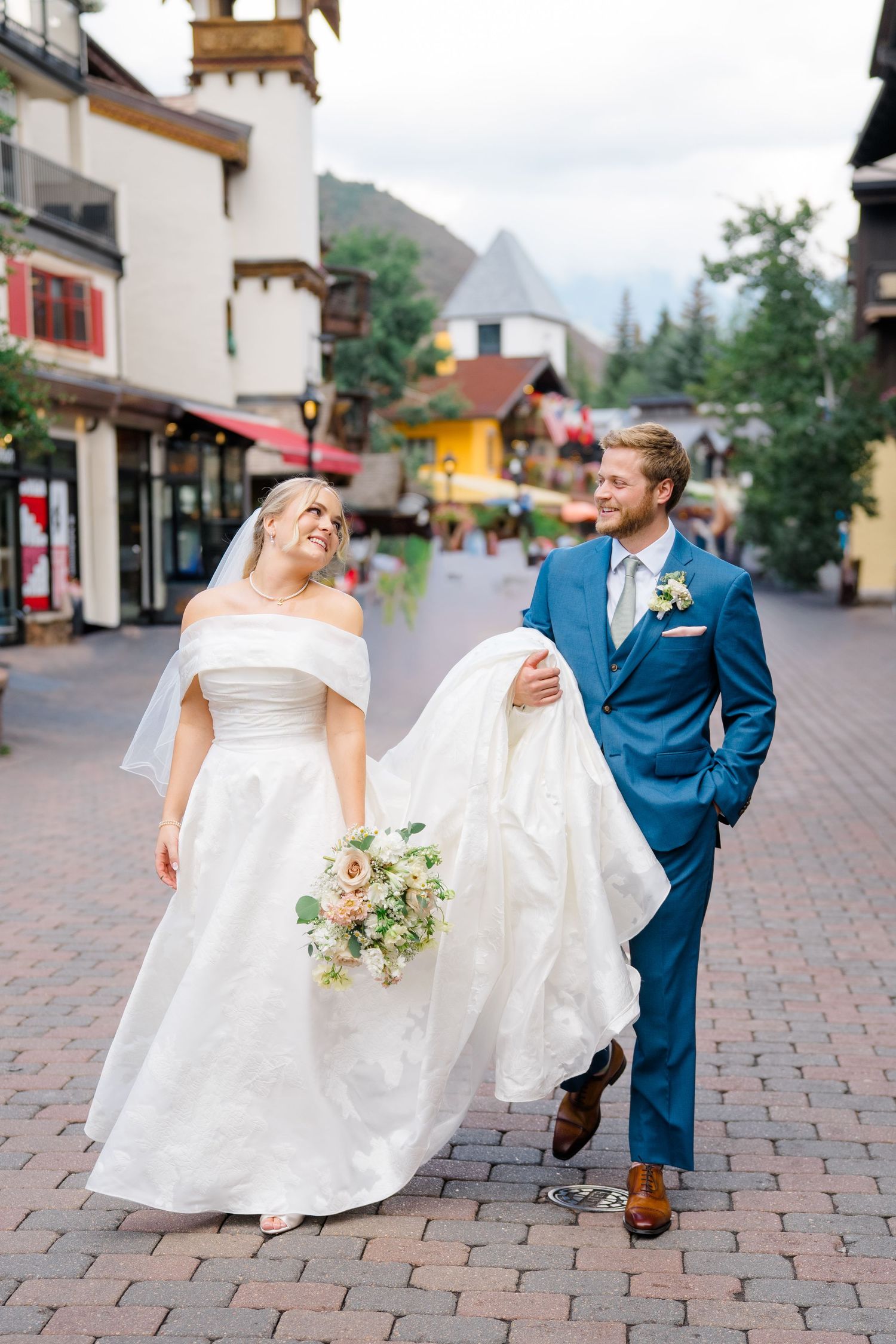 A romantic wedding couple dancing and twirling on brick pavers in a charming mountain town setting.