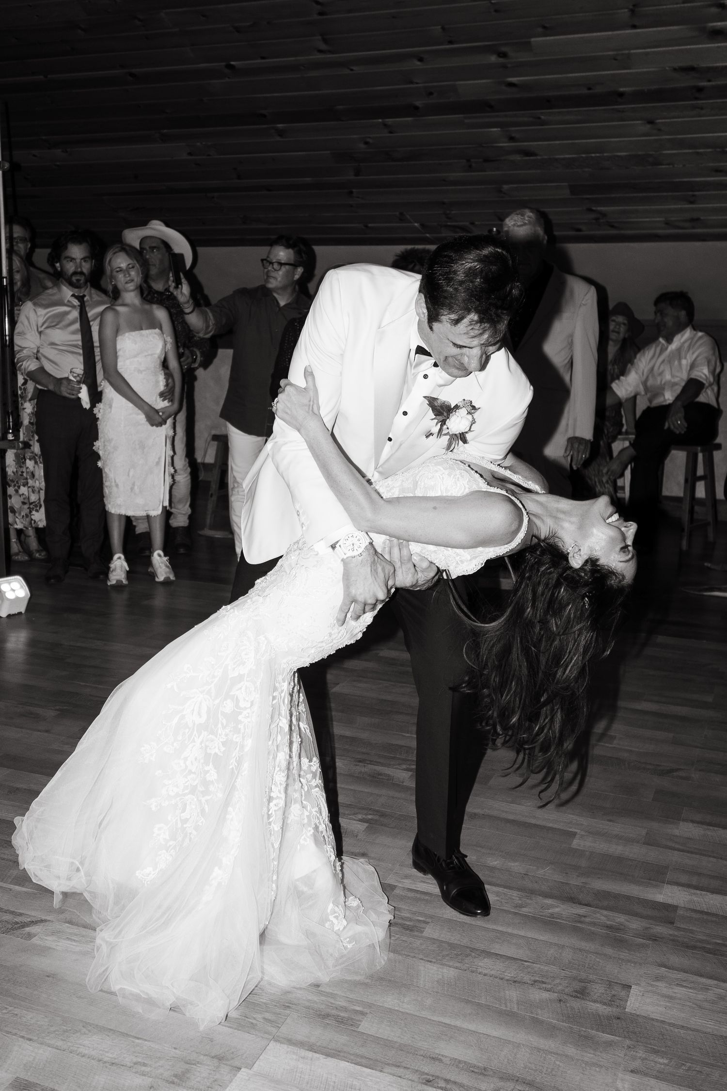 A sequence of black and white photos showing a couple performing a dramatic dance dip move on a wooden dance floor.