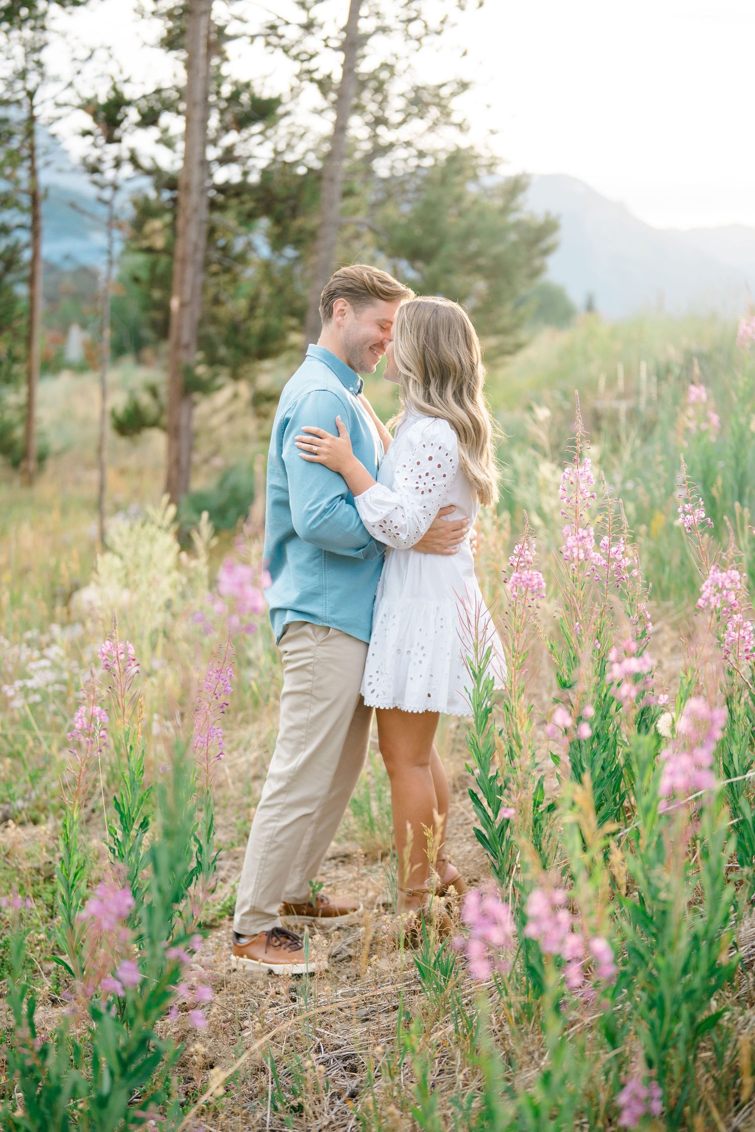 Lake Dillon Engagement photos - A couple shares romantic moments among blooming pink wildflowers in a mountain meadow at sunset.