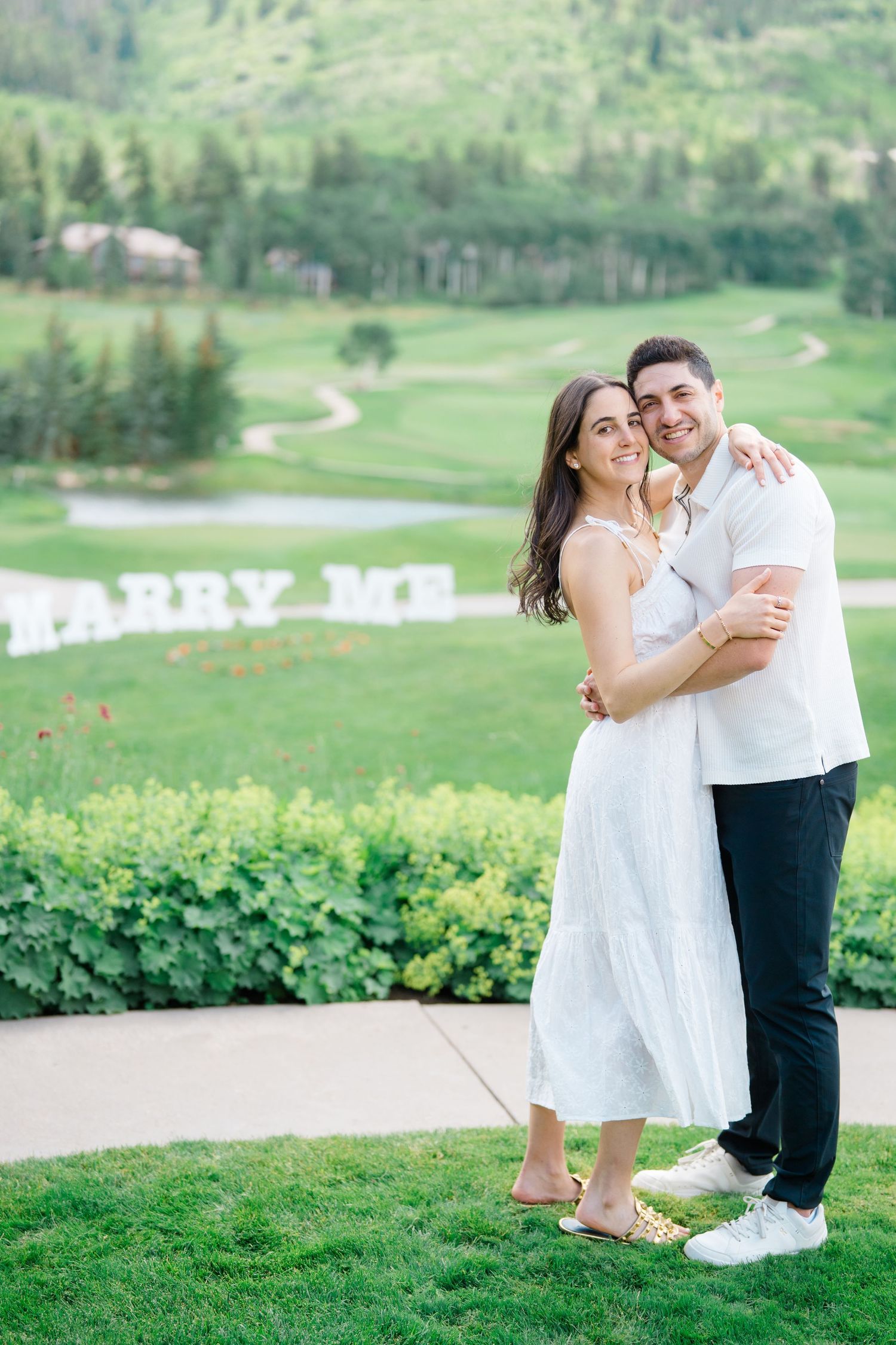 A couple shares intimate moments on a lush green golf course during a summer photoshoot.