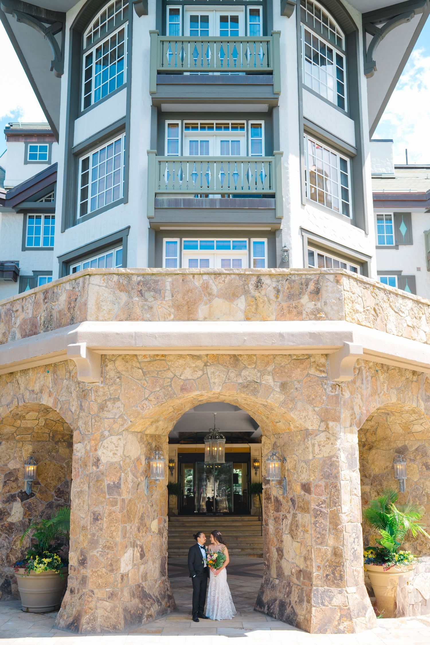 An architectural wedding photo series featuring a stone and blue building facade with arched details.