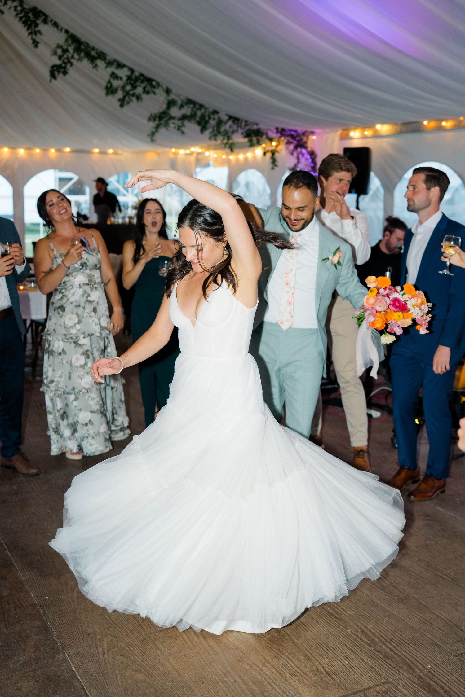 Wedding couple spins on the dance floor during their first dance under a decorated tent.