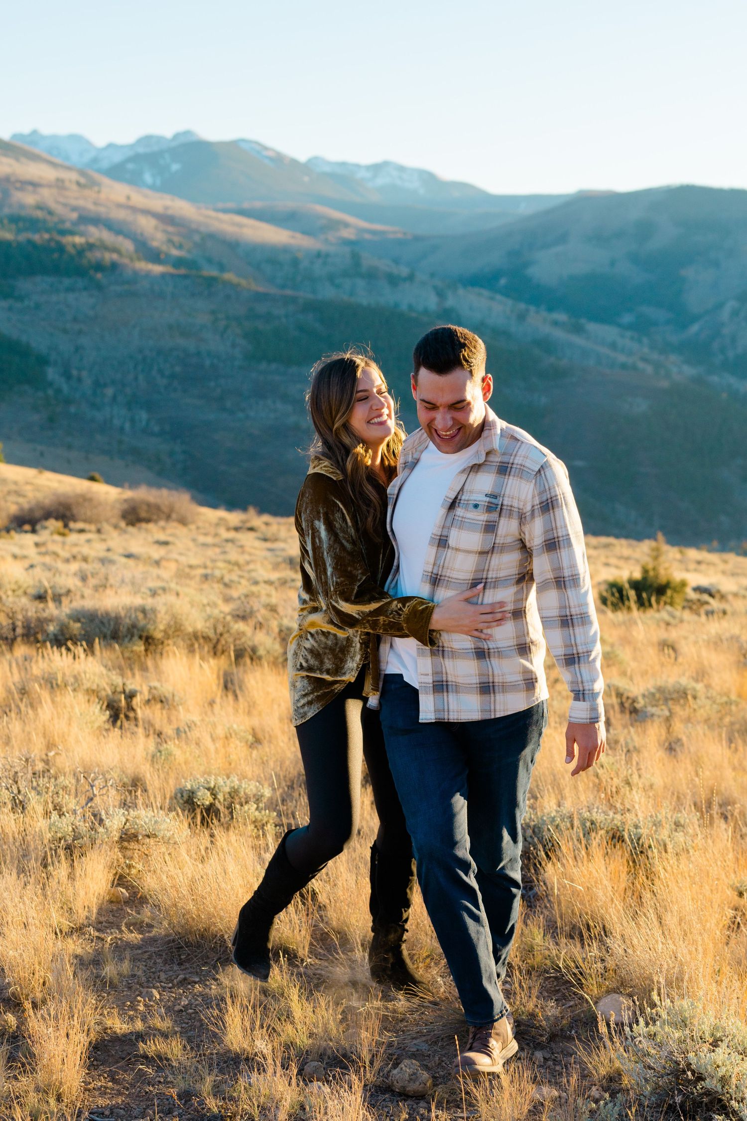 Couple enjoying a romantic moment together in a golden mountain meadow at sunset.