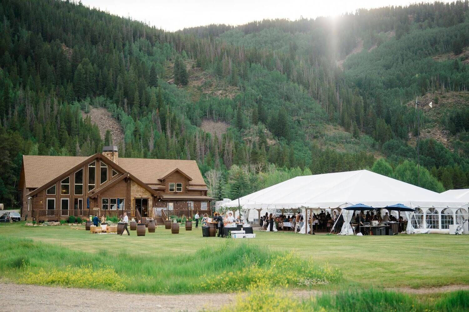 Camp Hale Wedding venue nestled in a scenic mountain valley with white tents and wooden lodge buildings.