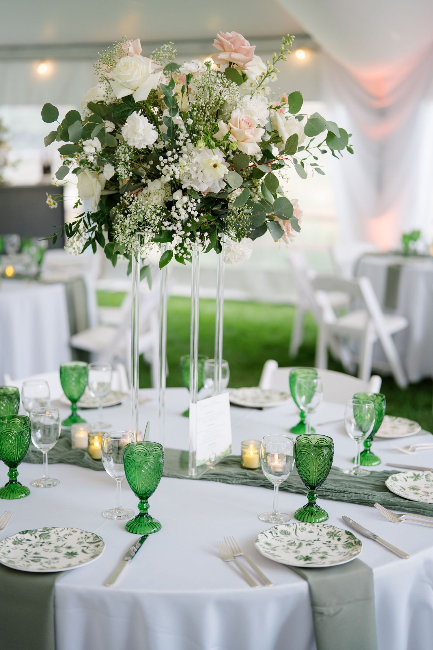 Elegant wedding reception table settings with green goblets and white floral centerpieces on tall stands at vail wedding.