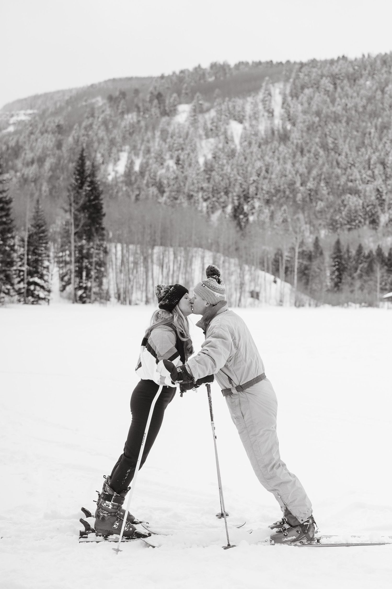 black and white photo guy and girl kissing on their skis
