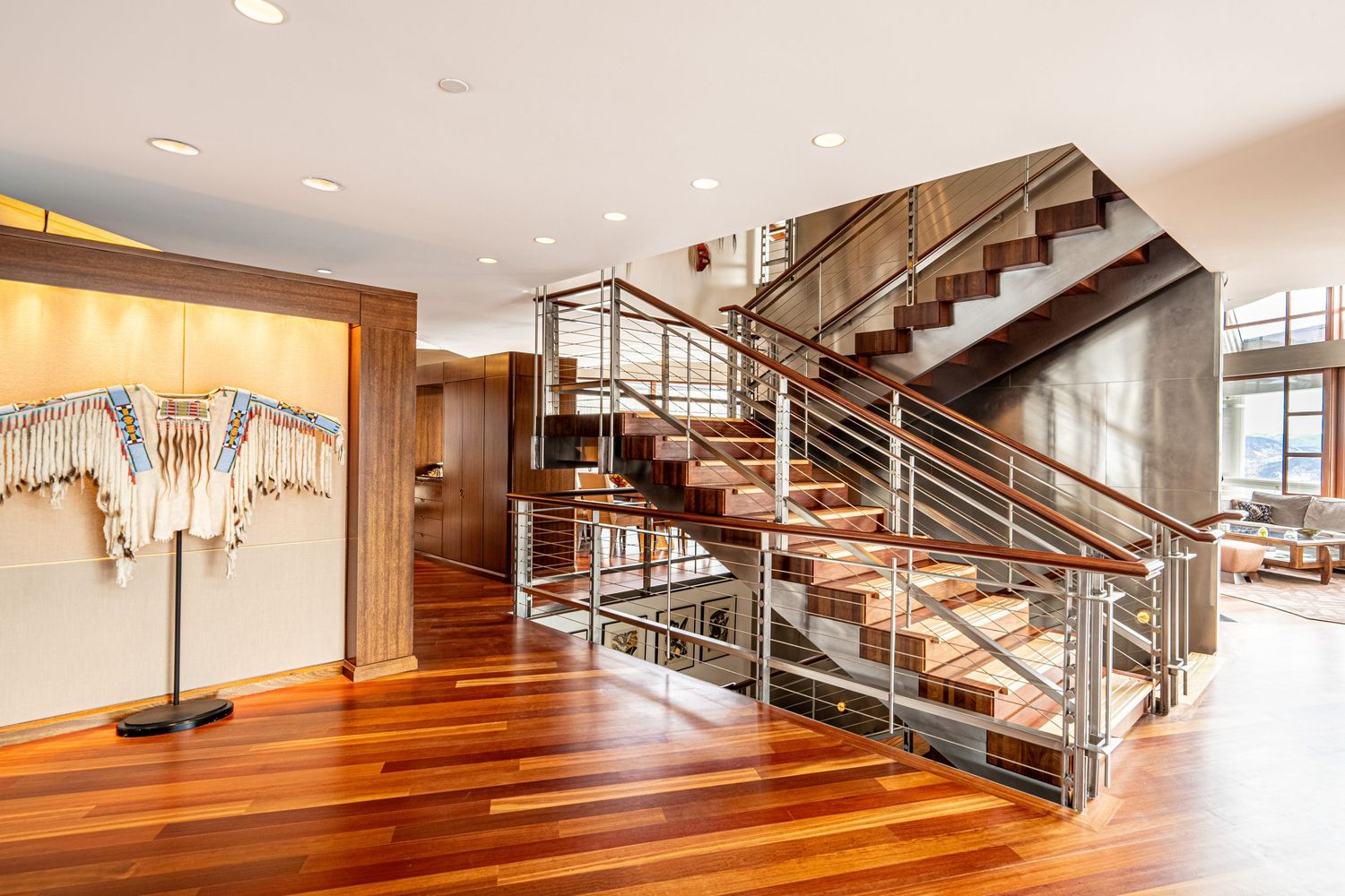 Modern staircase with wood flooring and metal railings in an open floor plan.