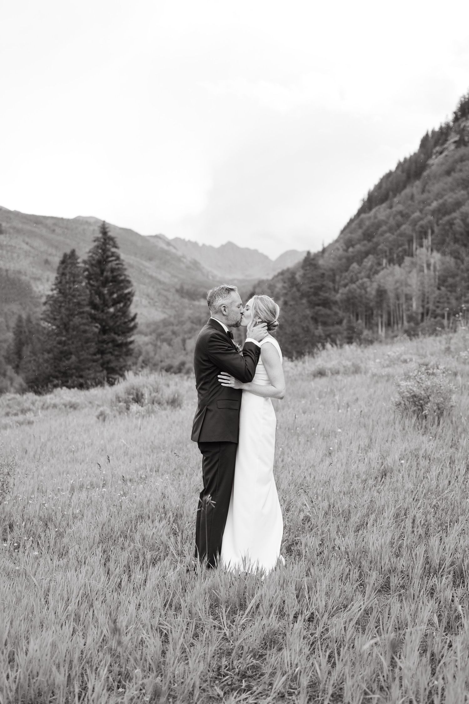 bride and groom kissing at wedding in front of the mountain