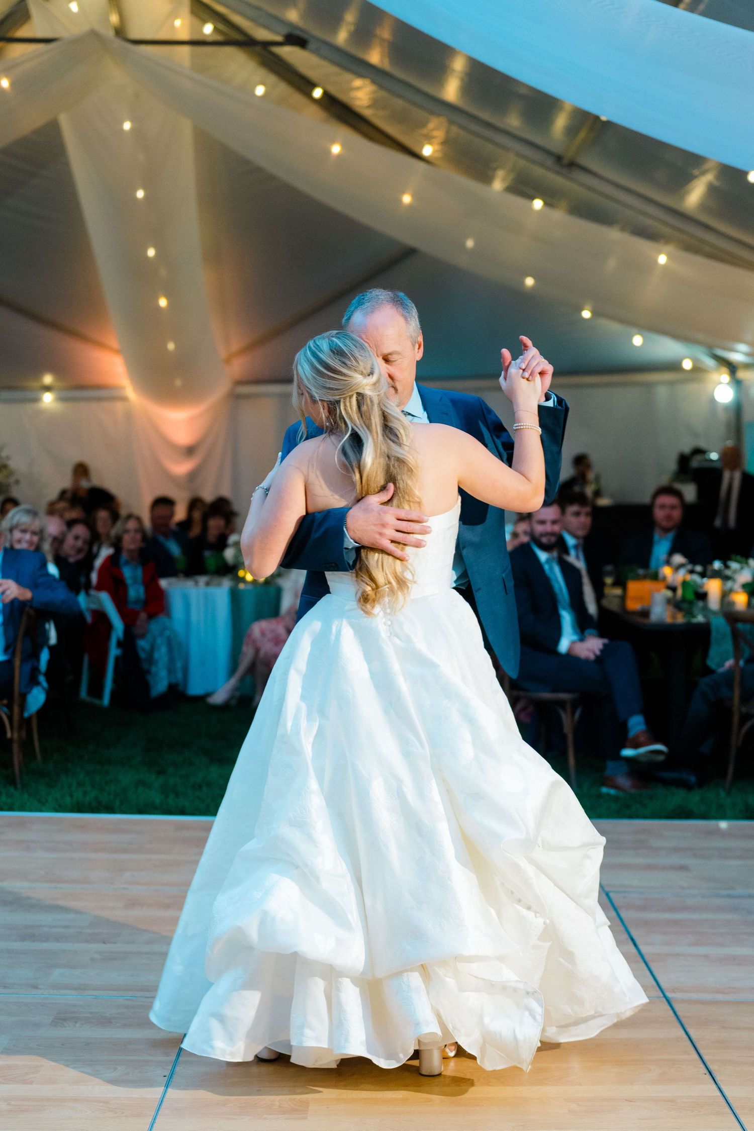 Two dancers in white dresses twirling gracefully on a dance floor under twinkling lights at an evening event at vail wedding at lionshead.