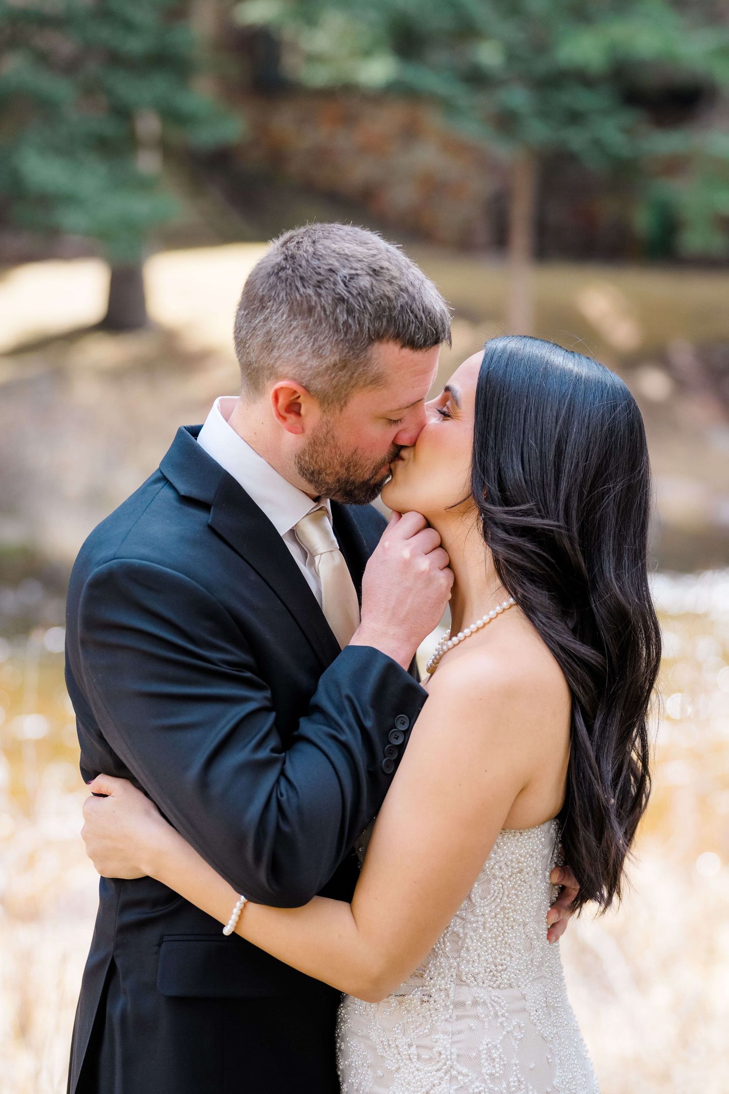 Sonnenalp Vail Wedding Venue - A bride and groom share a romantic kiss outdoors, with the groom in a dark suit and bride in a lace gown.