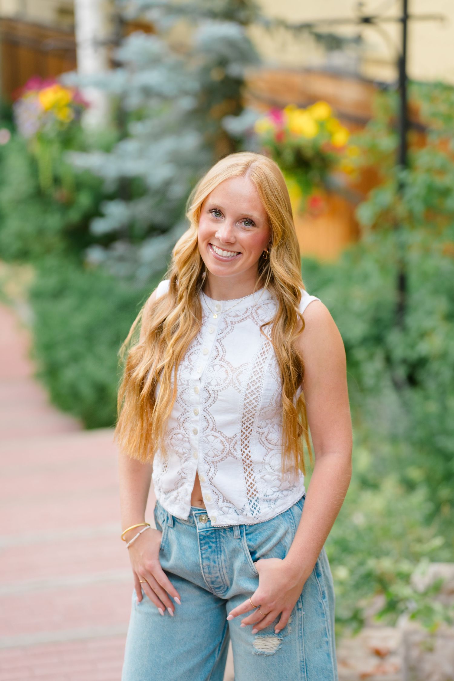Summer fashion look with white lace top and distressed jeans in a garden setting during vail senior photography session.
