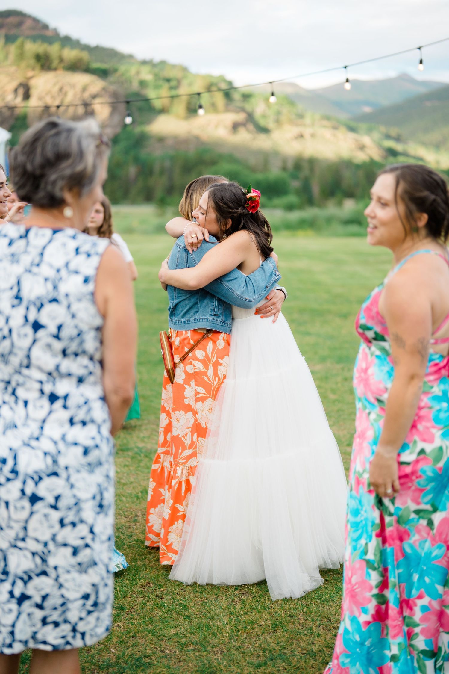 Wedding party in vibrant floral dresses dancing and celebrating outdoors.