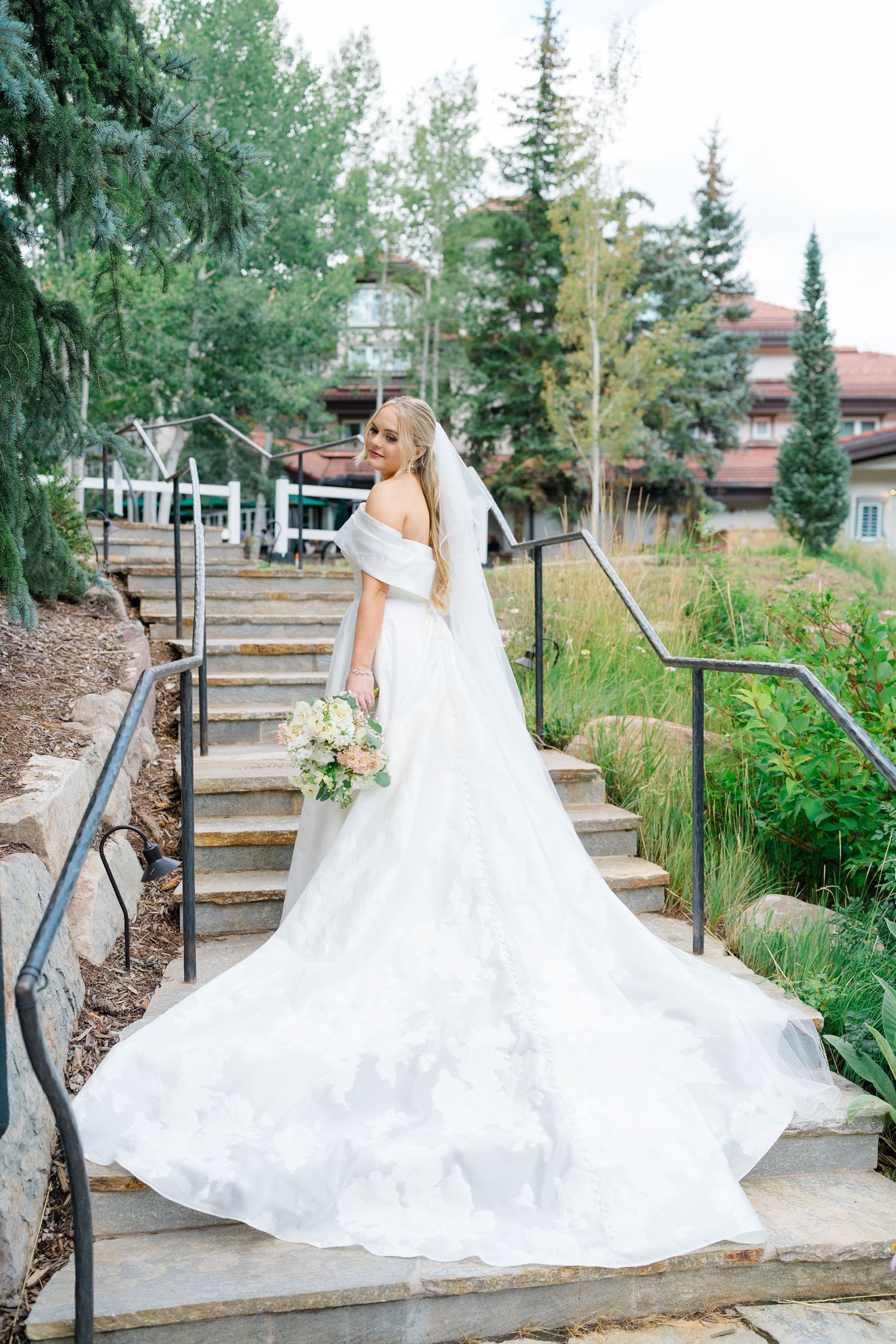 A stunning bridal portrait series showing a flowing white wedding gown cascading down outdoor garden steps.
