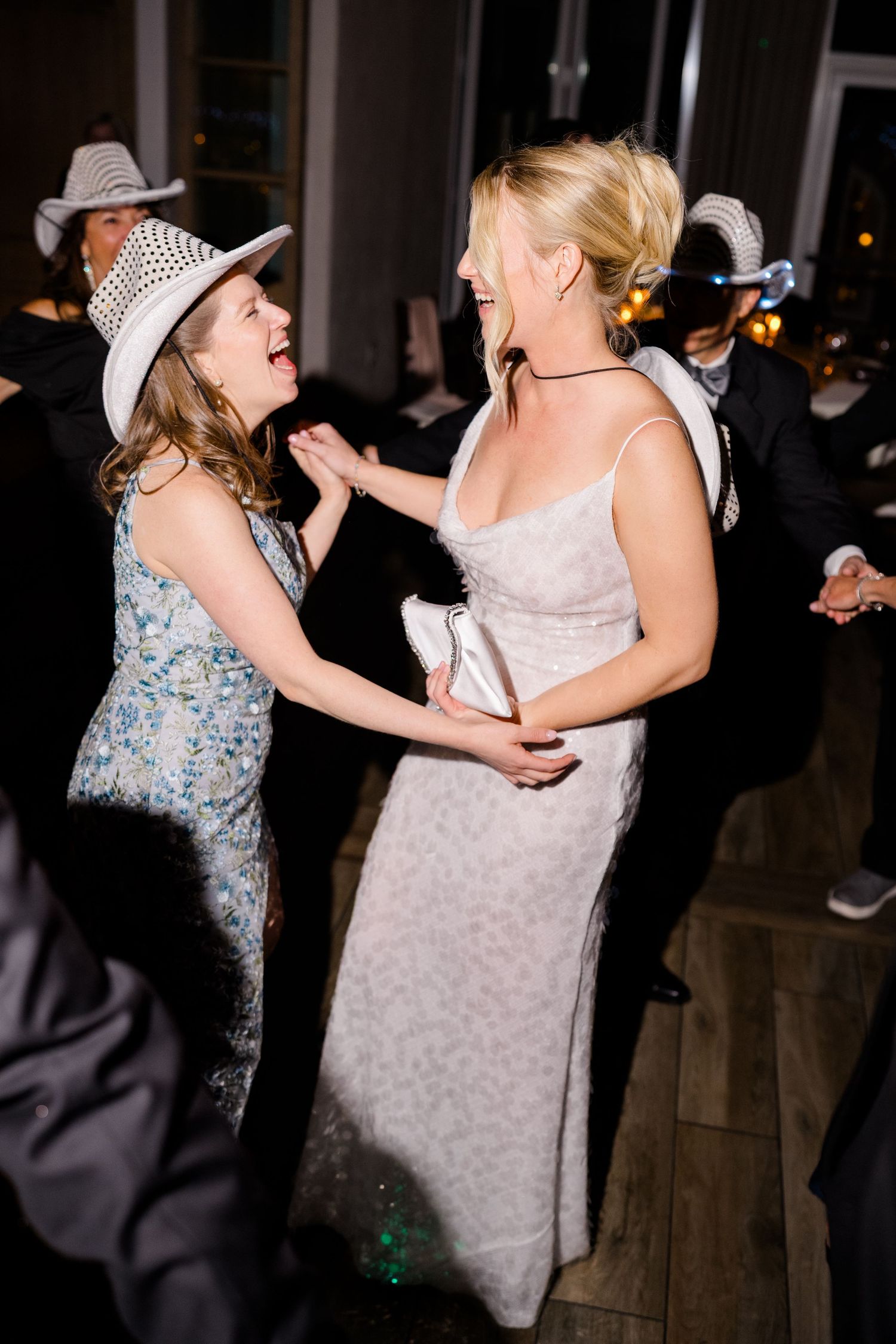 Two women in elegant dresses and cowboy hats laugh and dance together at a formal party event at Vail Sonnenalp Wedding.