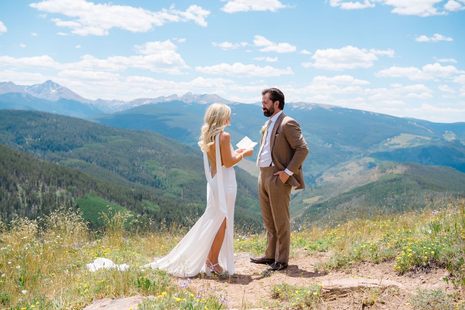 Bride and groom exchange vows on a mountain summit with stunning Rocky Mountain views on their wedding day.