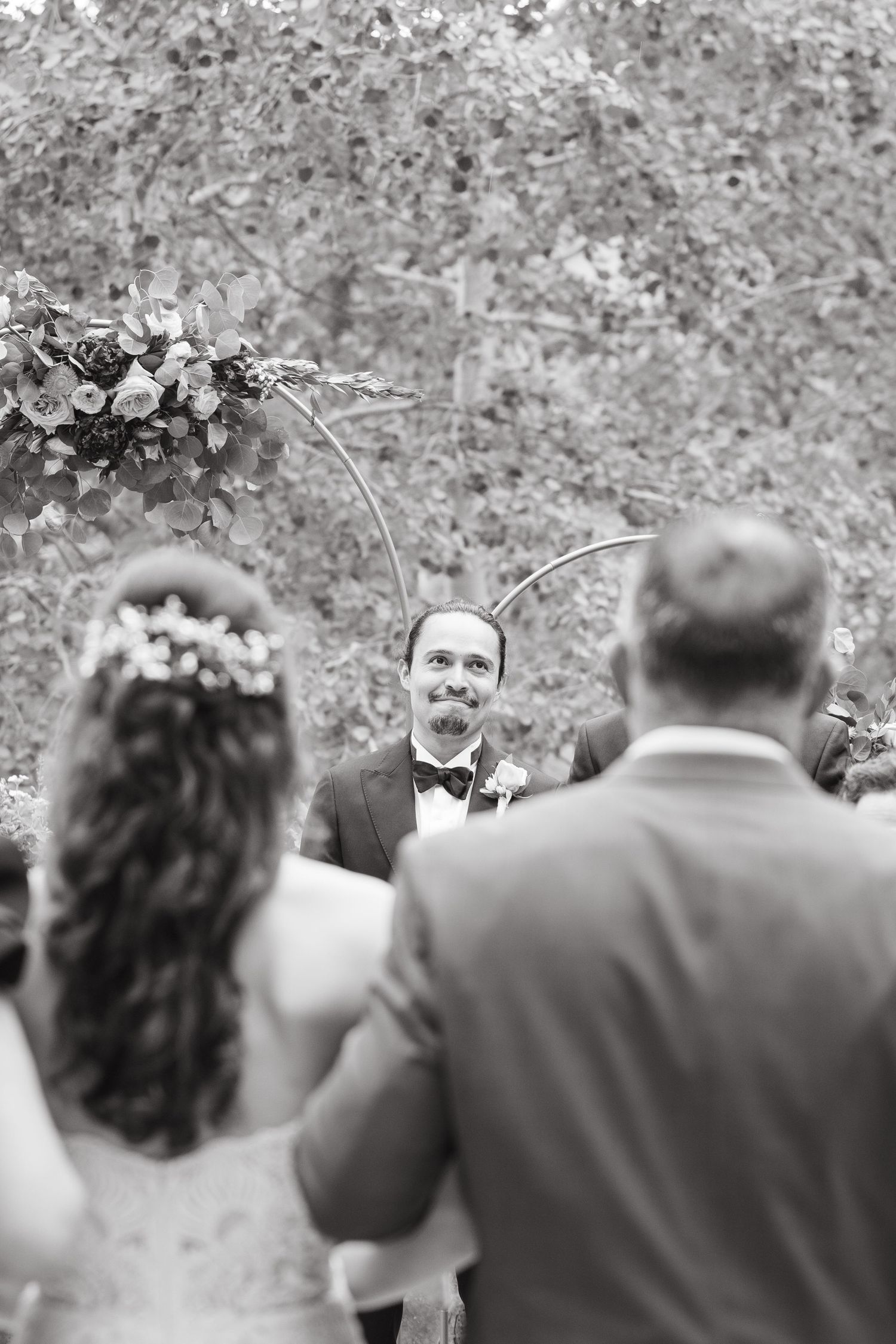 A black and white panoramic sequence showing wedding guests seated outdoors during a ceremony.