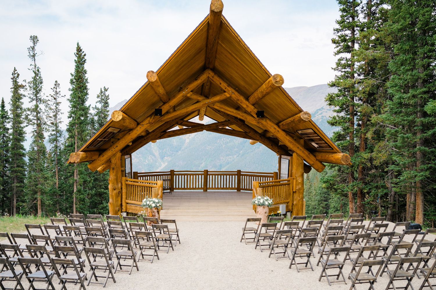Rustic wooden wedding ceremony setup with rows of chairs and timber frame arch in an outdoor mountain setting at copper mountain.
