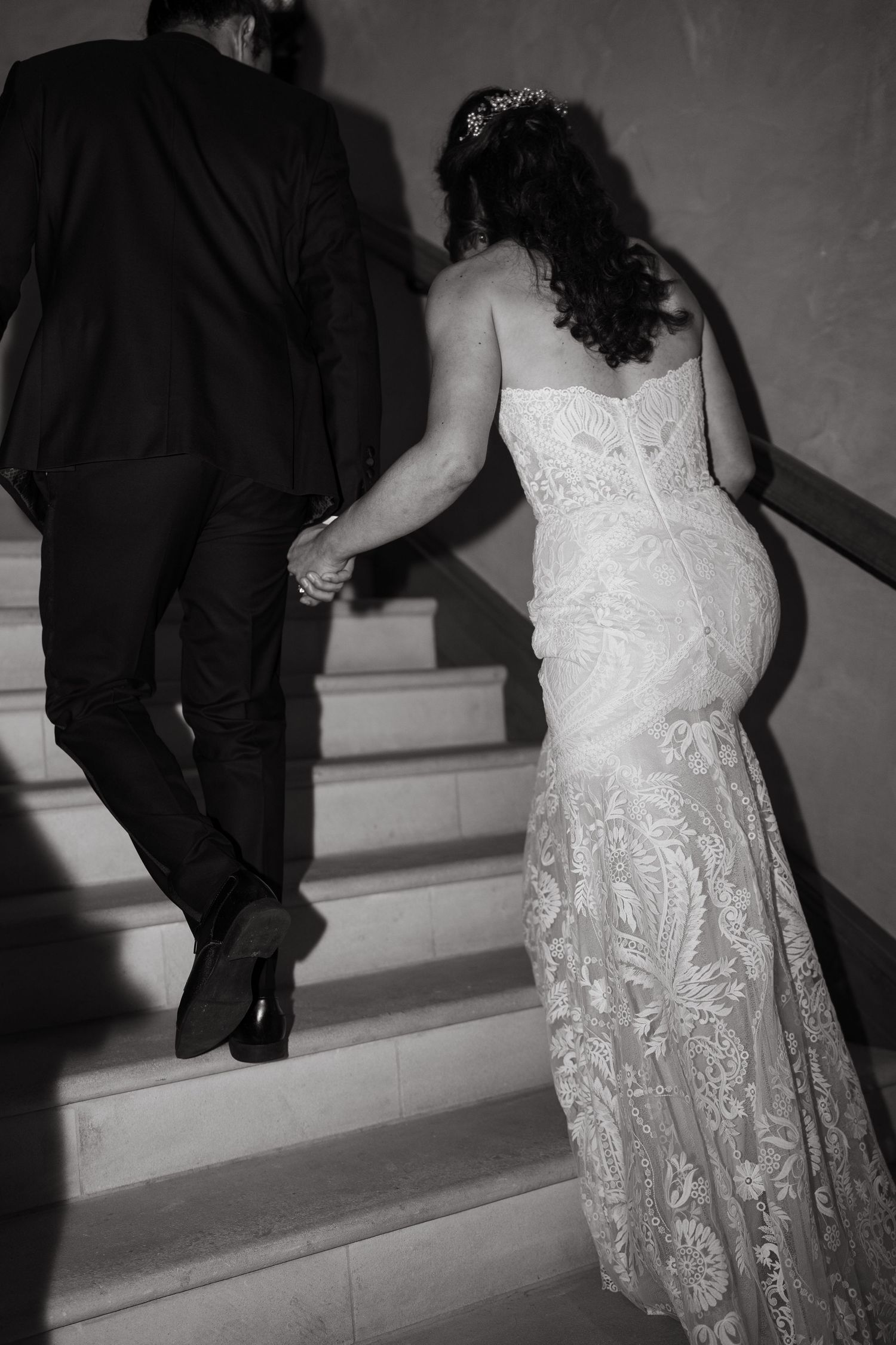 Black and white image sequence showing a couple ascending stairs with the bride wearing a detailed lace wedding dress.