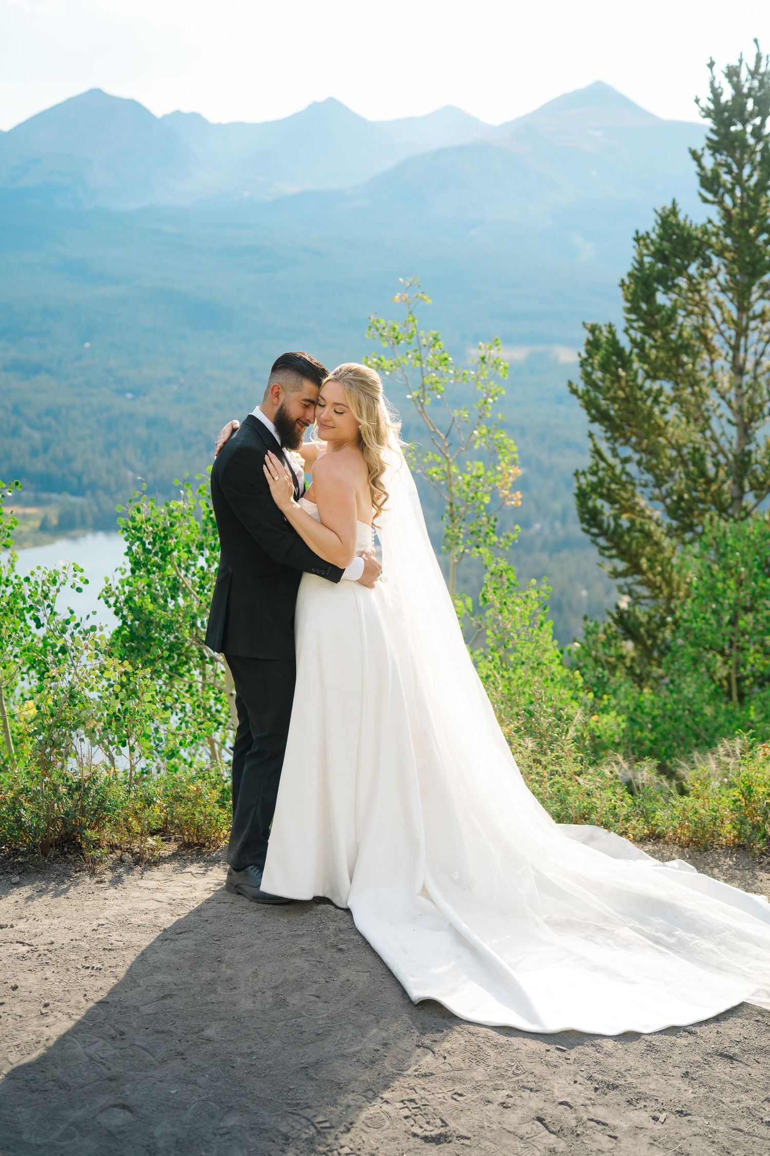 A couple shares an intimate moment overlooking a scenic mountain lake vista on their wedding day.