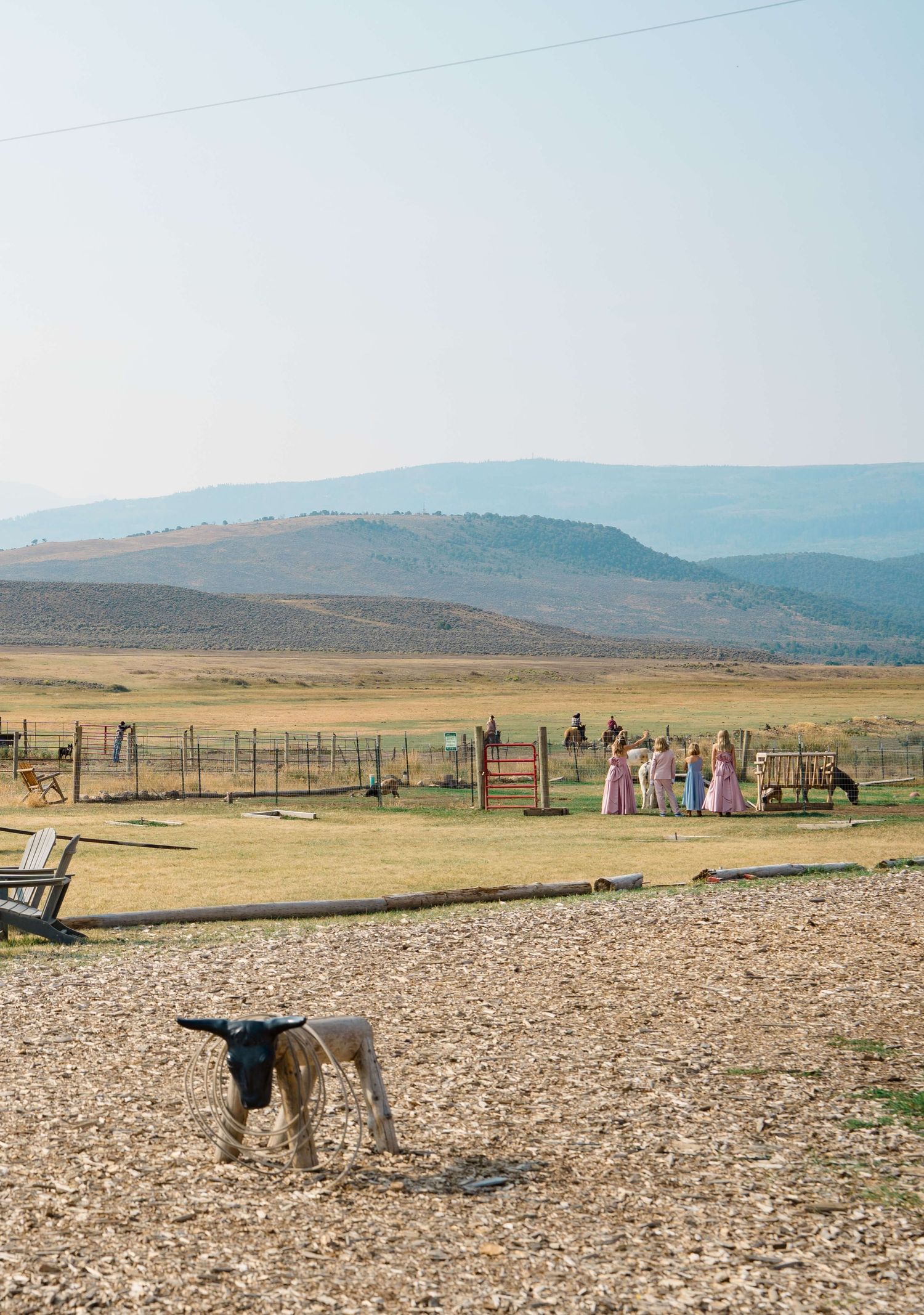 4 Eagle Ranch Vail Wedding Venue - party in pink dresses gathered near ranch fence with longhorn cattle and vast open plains backdrop.