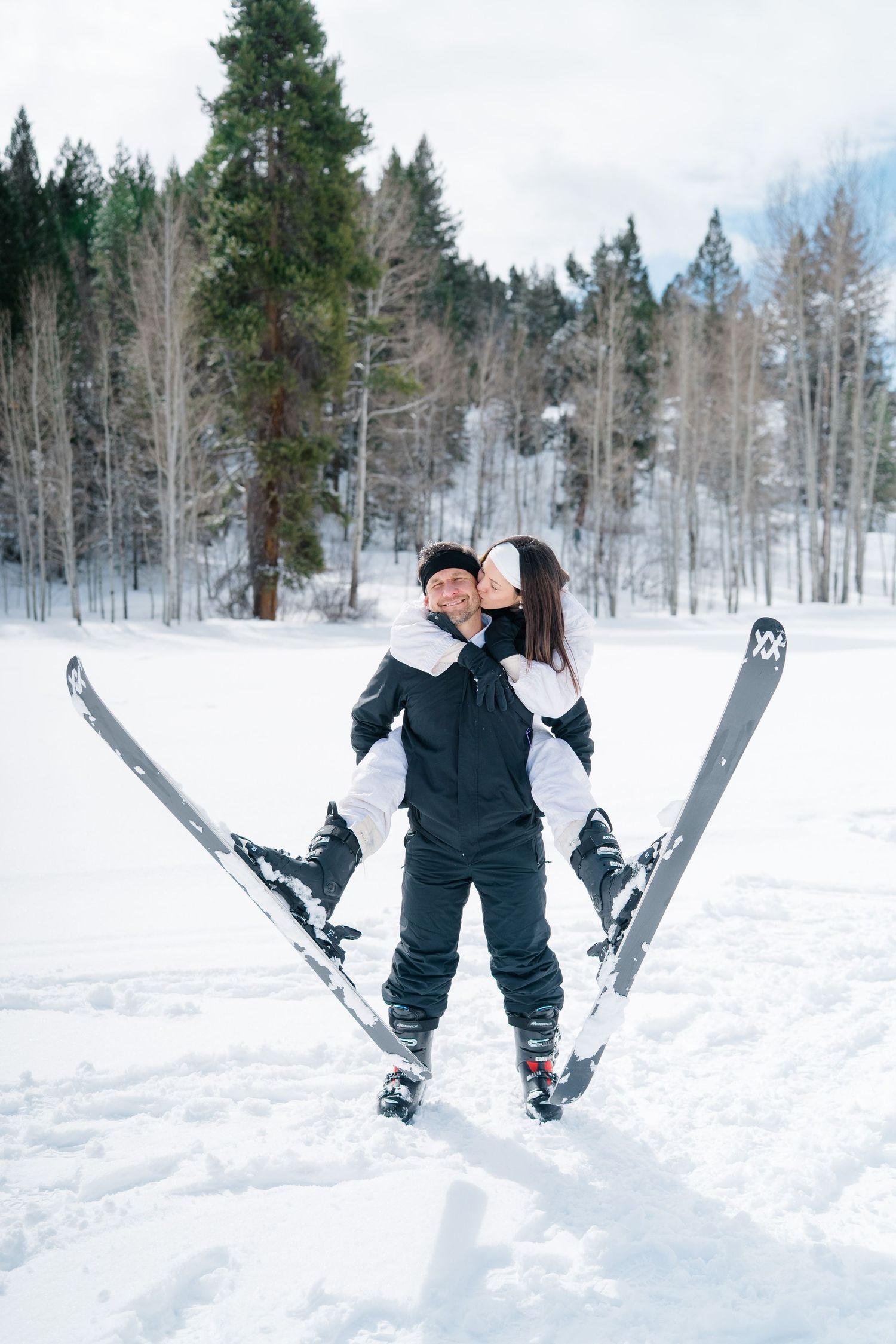 A playful sequence showing a couple falling backwards into deep snow while wearing winter ski gear during vail proposal.