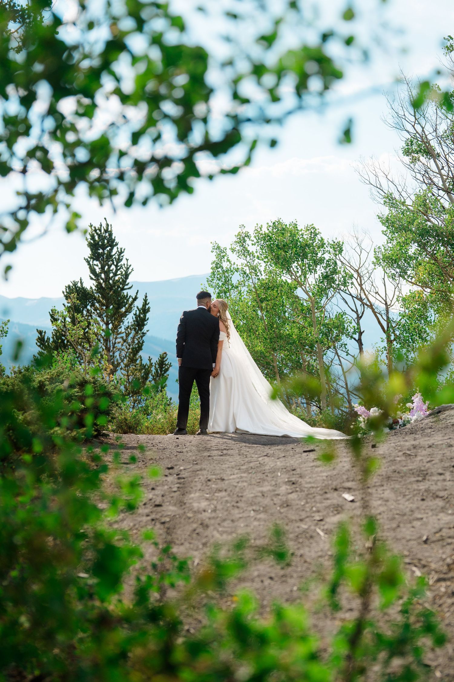 A romantic wedding couple stands atop a sandy hill surrounded by lush greenery on their special day during Breckenridge micro wedding.