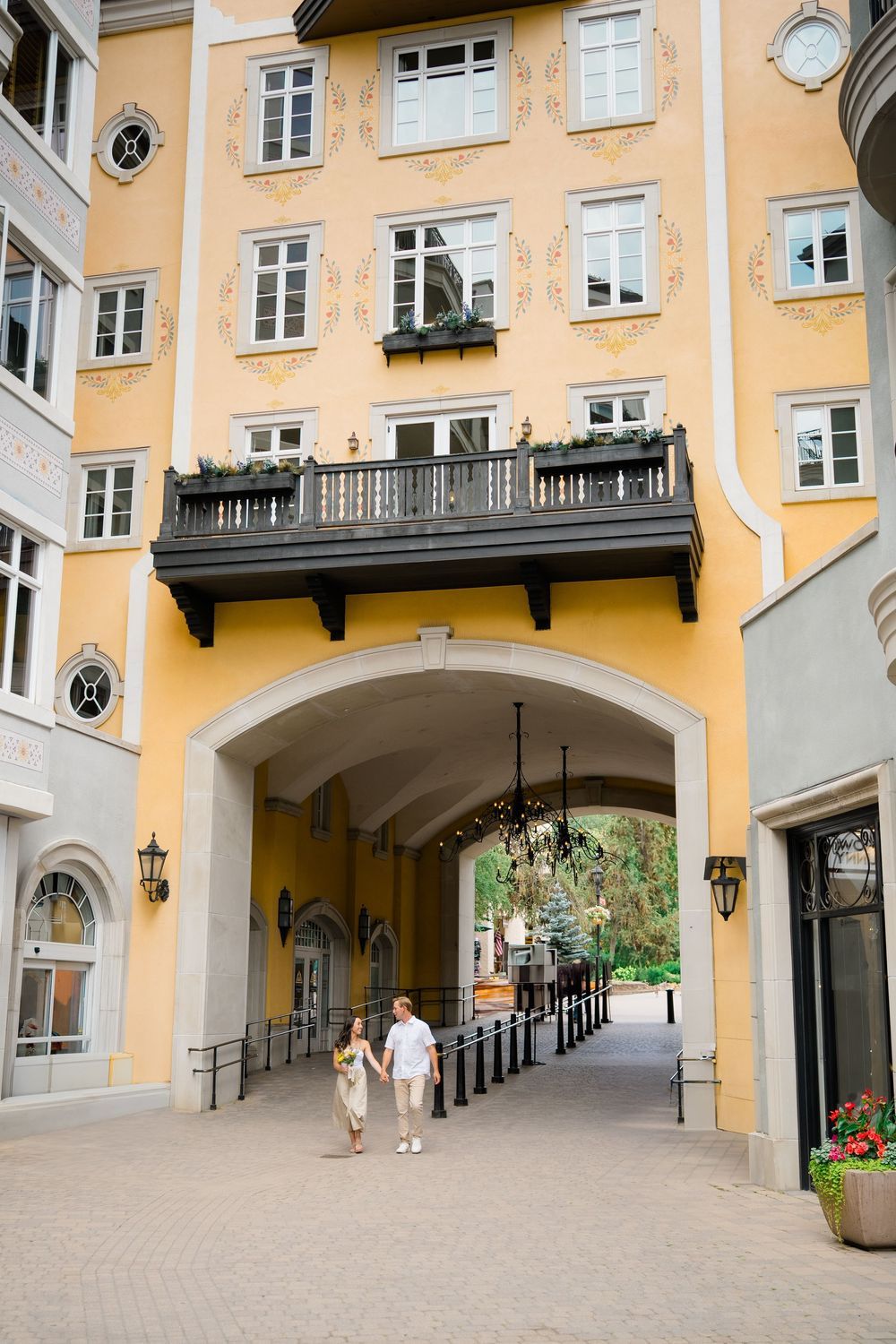 Yellow European-style courtyard building with arched passageways and traditional architecture in vail proposal photography session.