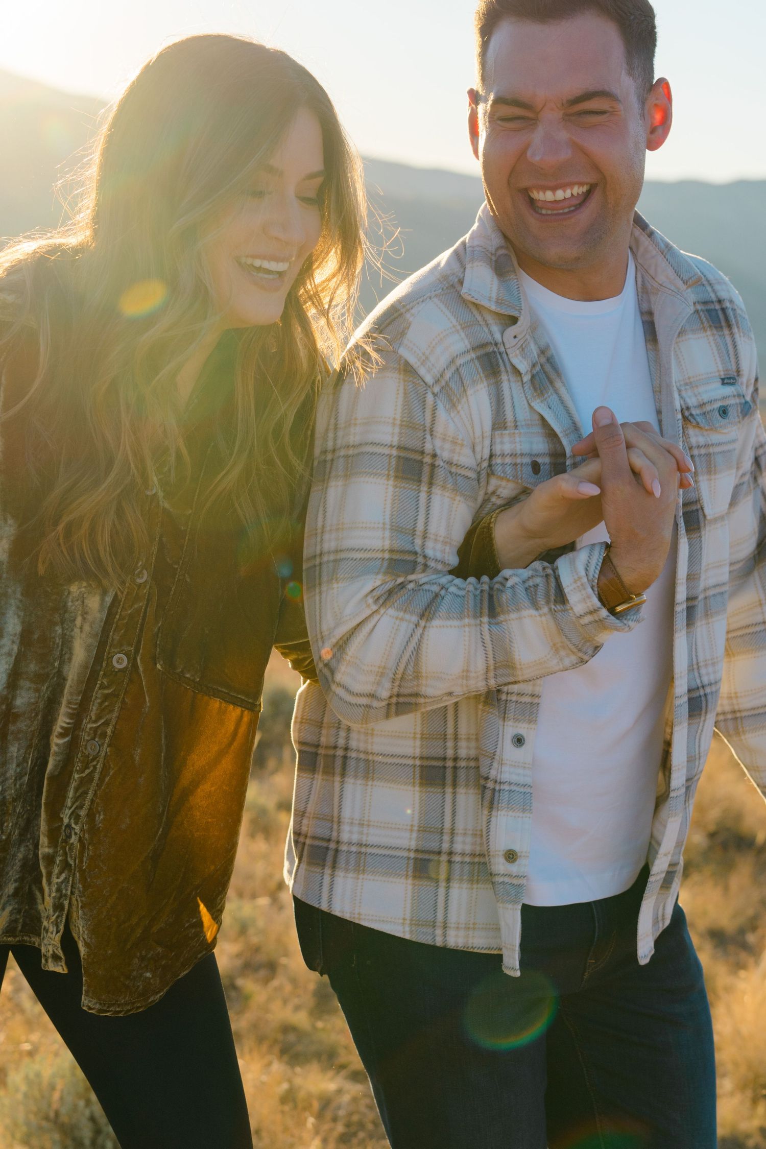 A couple shares joyful moments together during a sunset photoshoot in the mountains with golden light.