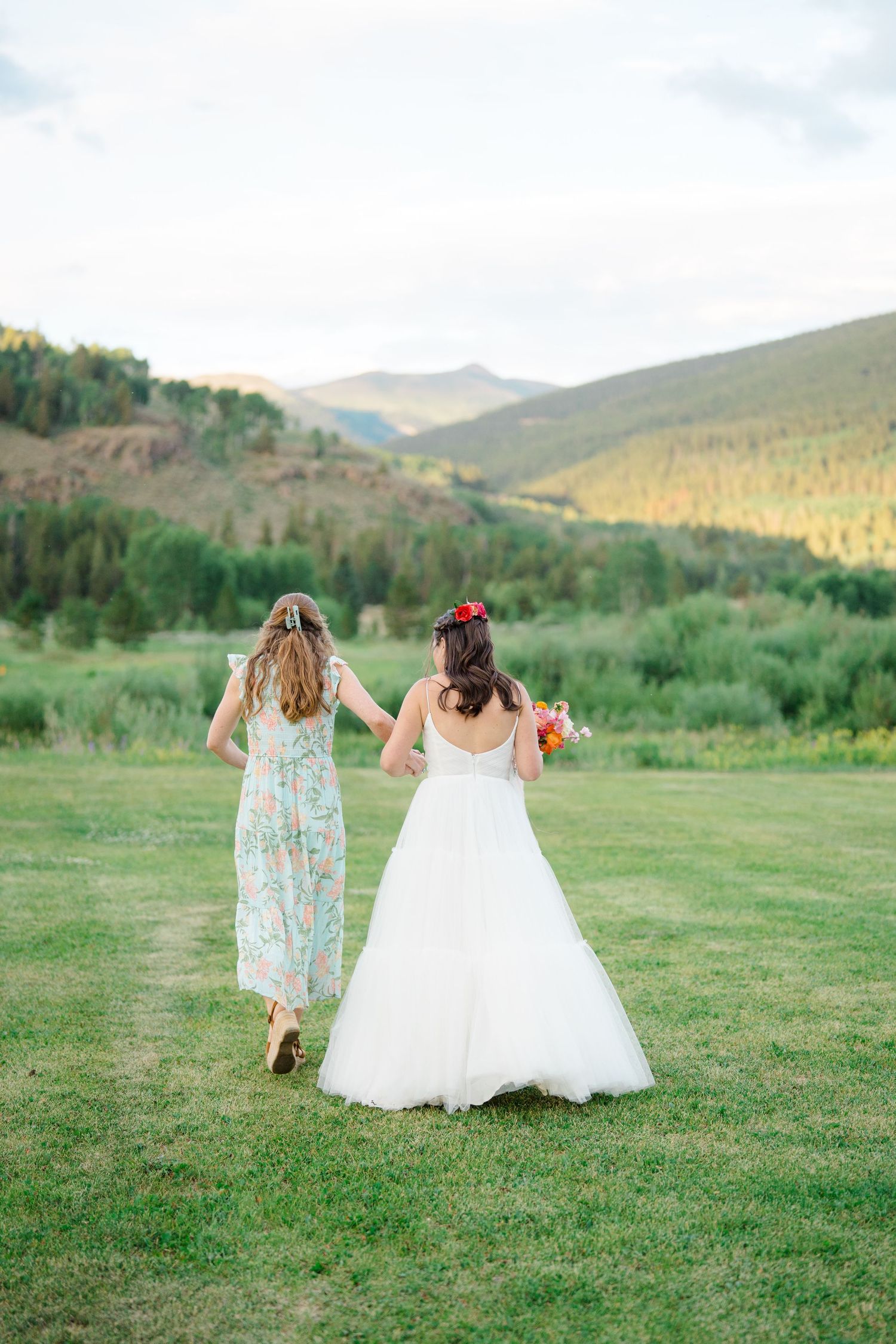 Wedding party walking through a scenic mountain meadow at sunset.