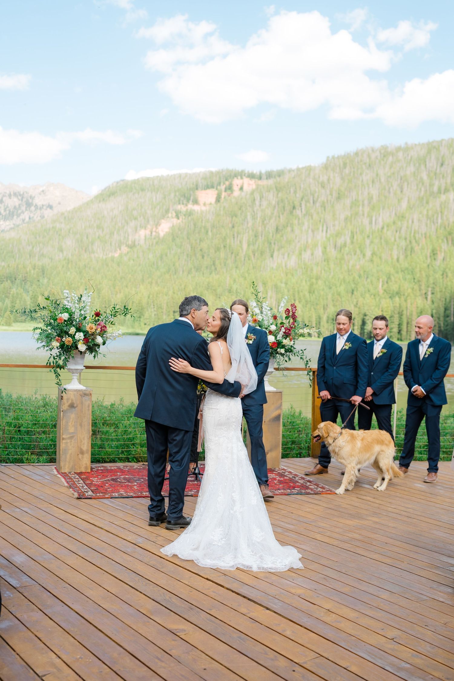 A wedding ceremony sequence shows a couple sharing their first kiss as a dog walks across the wooden deck venue.