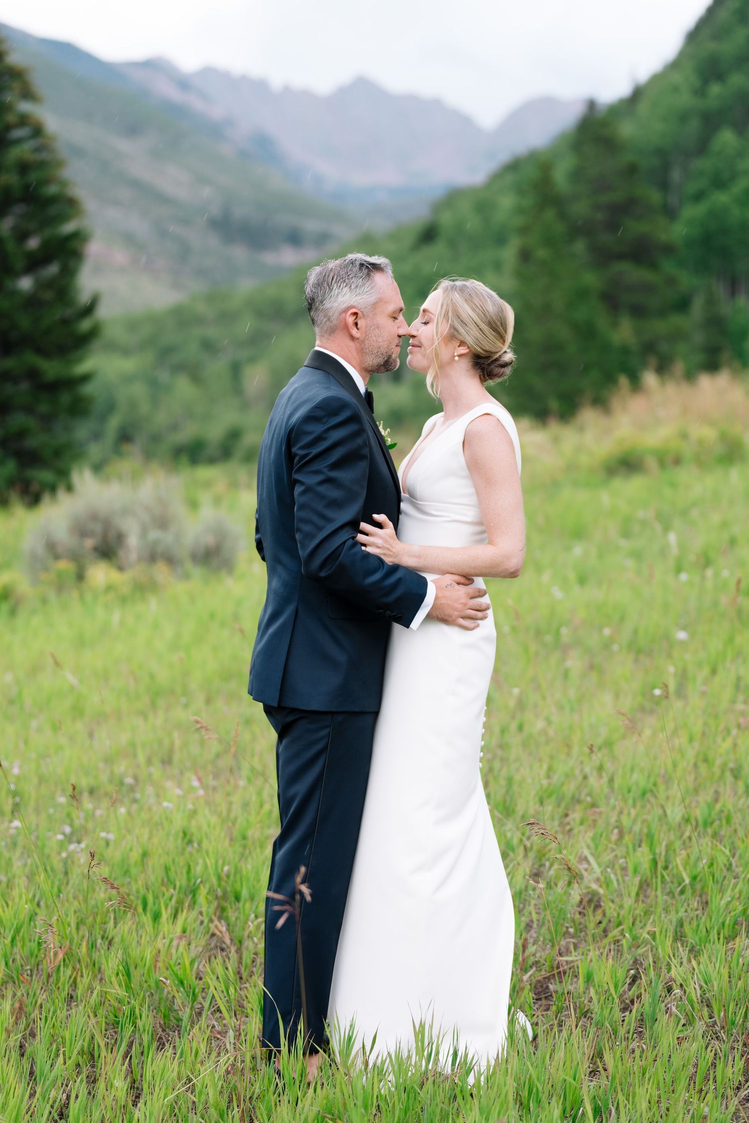 bride and groom touching noses in front of the rocky mountains