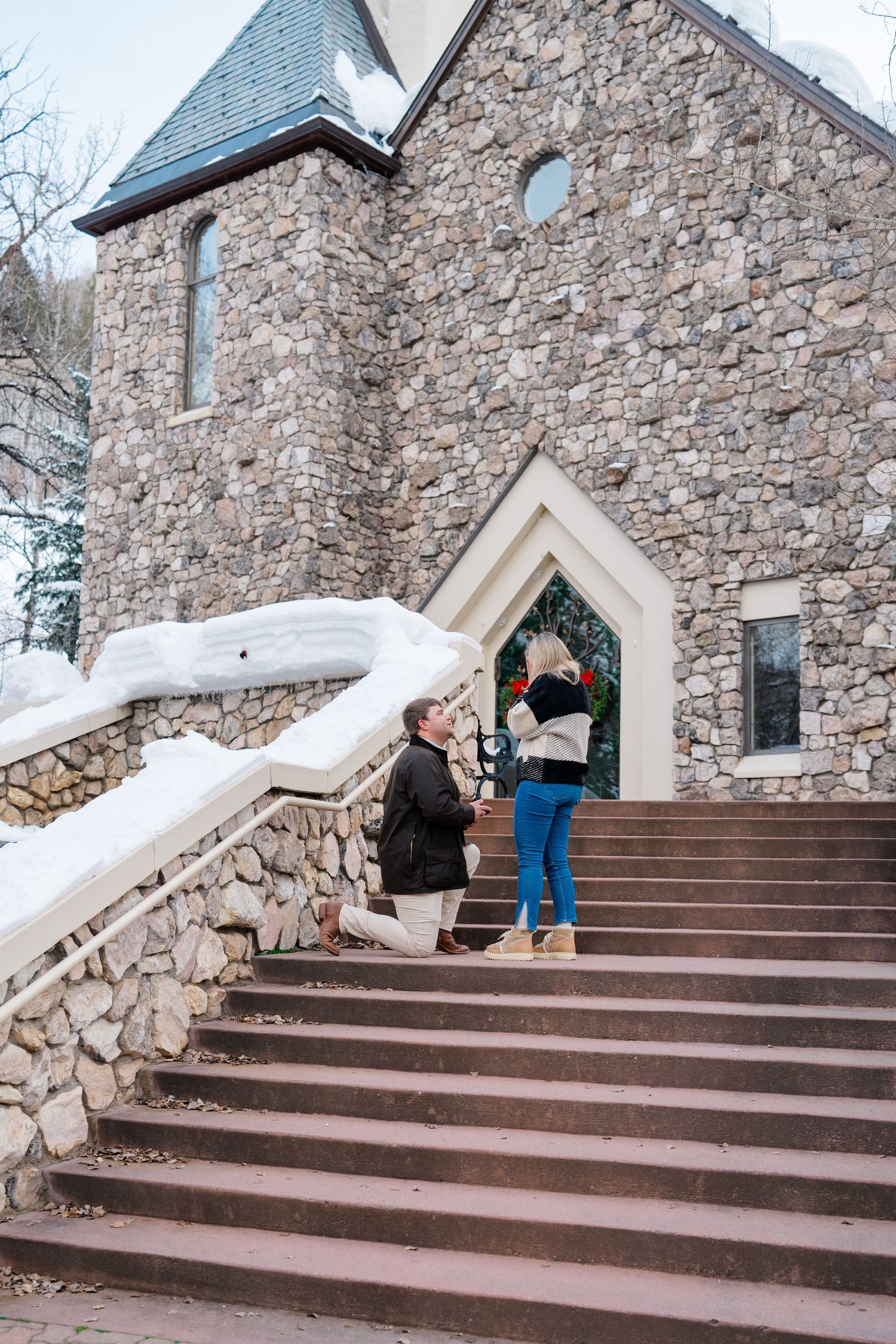 guy proposing to girl at beaver creek chapel in beaver creek colorado engagement on stone streets.