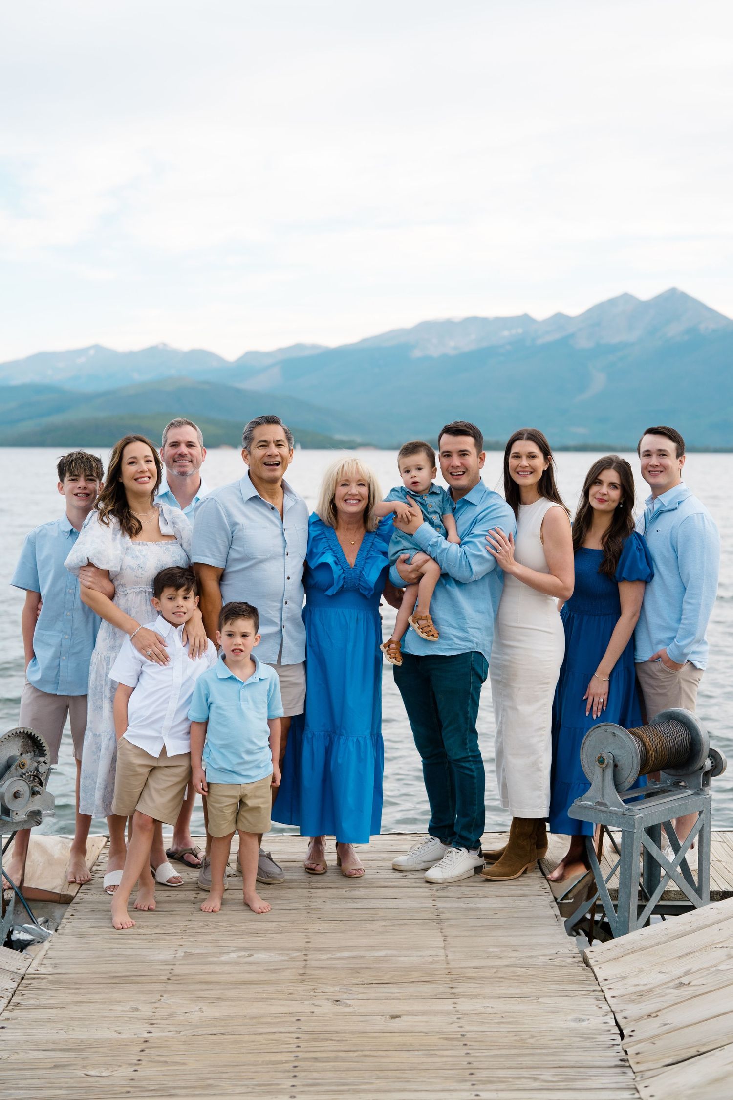 Lake Dillon Proposal - A group stands together on a wooden dock with mountains and a lake in the background on a sunny day.
