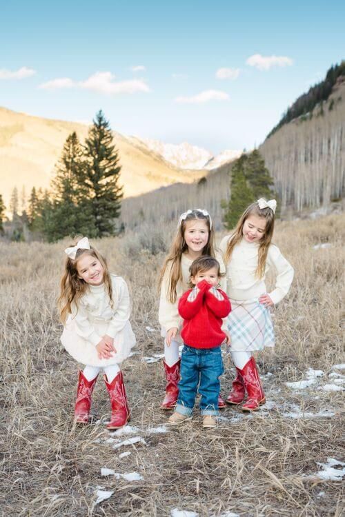 Two children in winter outfits play together in a scenic mountain meadow with snow and dried grass - best vail family photo locations