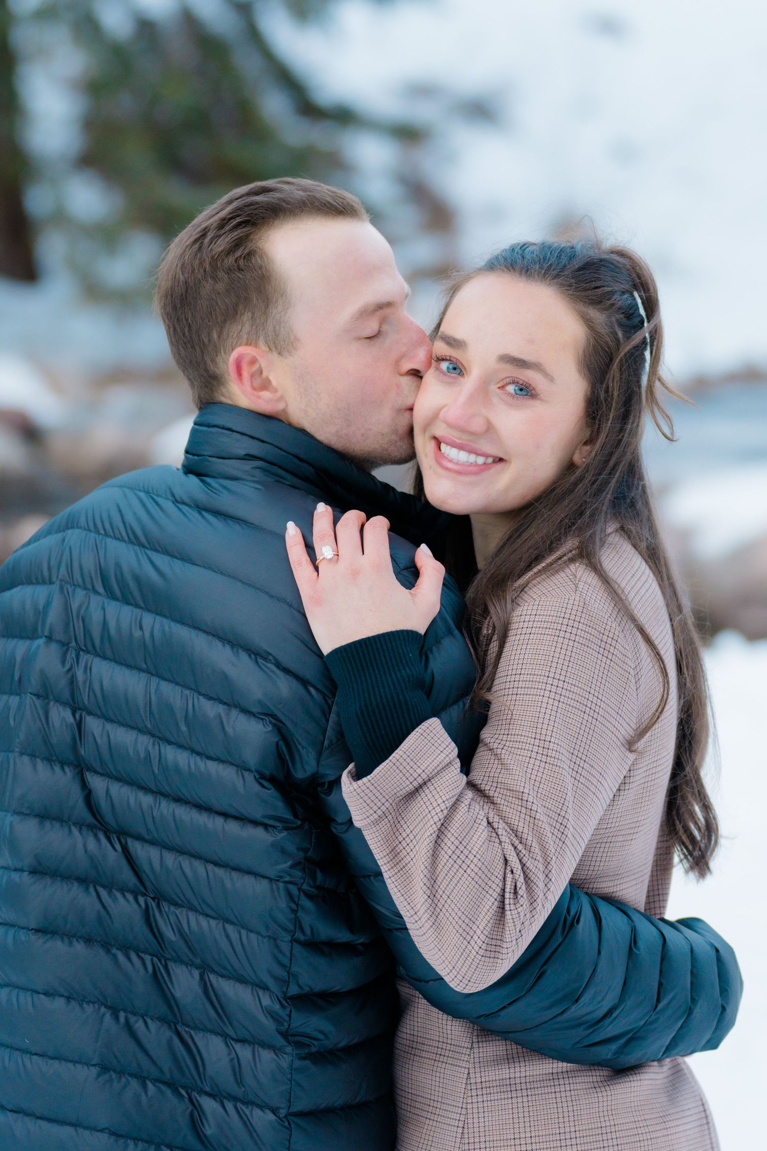 Romantic winter engagement photos showing couple embracing and sharing sweet moments in the snow.