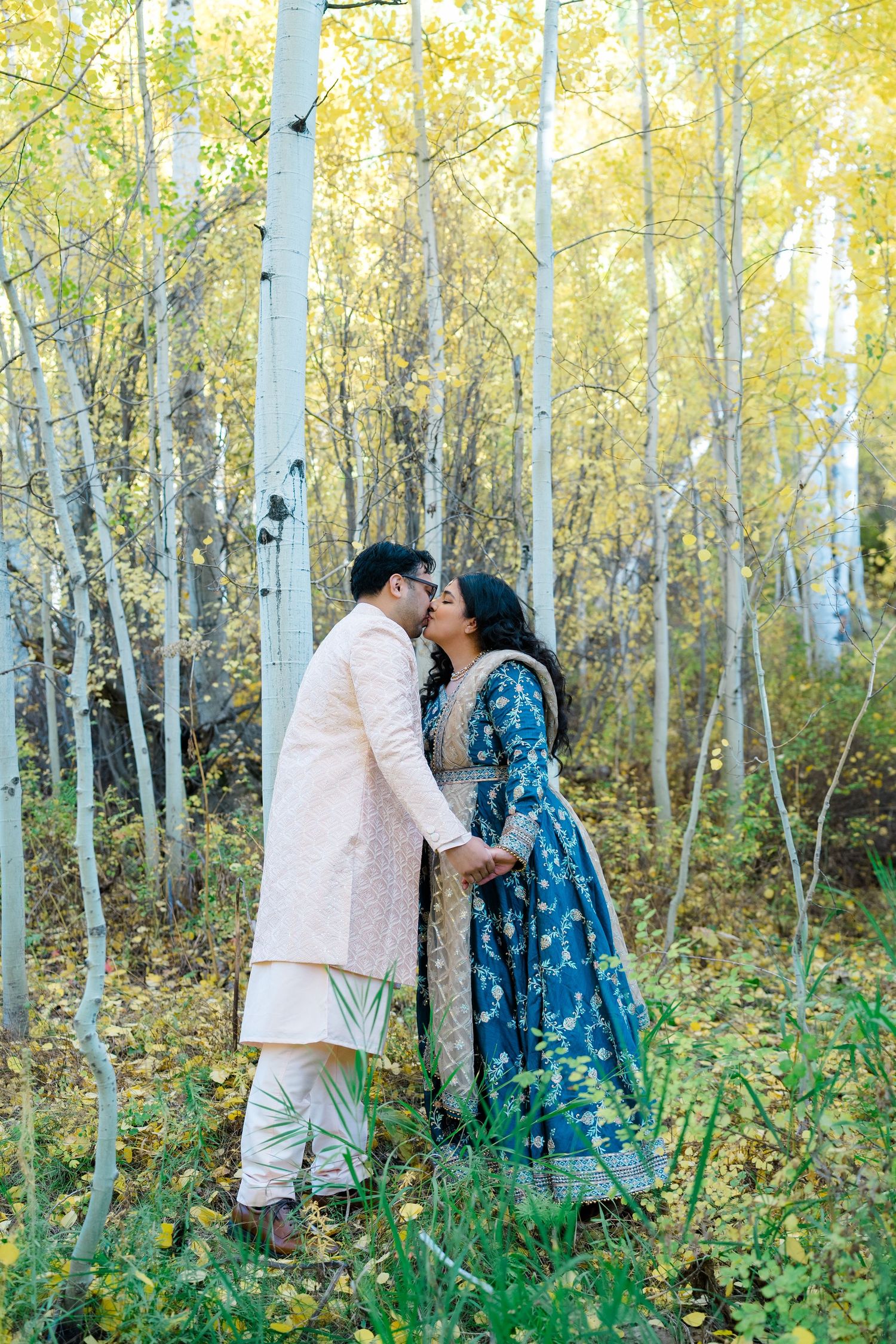 Romantic couple shares intimate moments among golden aspen trees in an autumn forest setting.