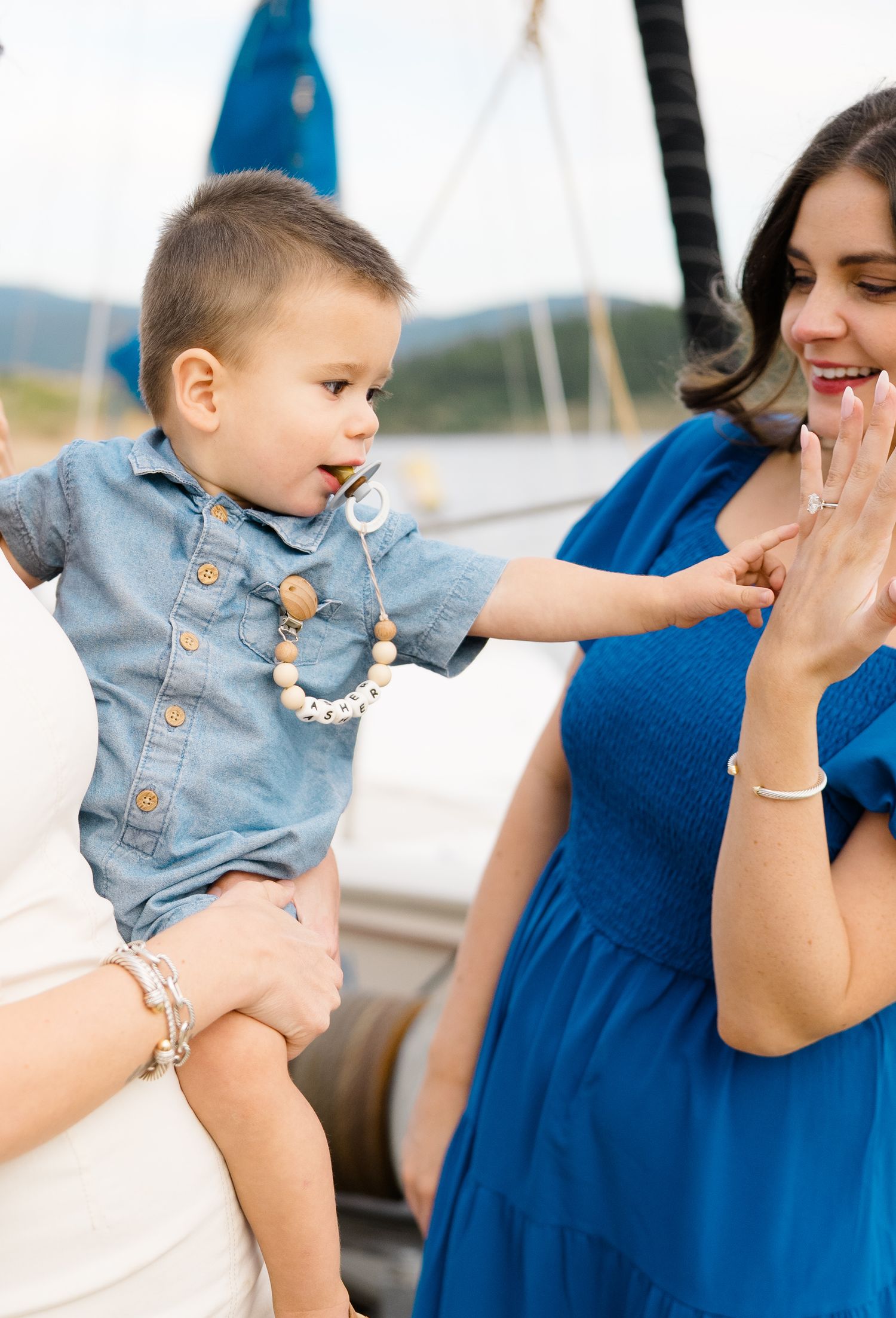 Sweet candid moment between a toddler in denim and woman in blue dress at outdoor event at lake dillon marina.