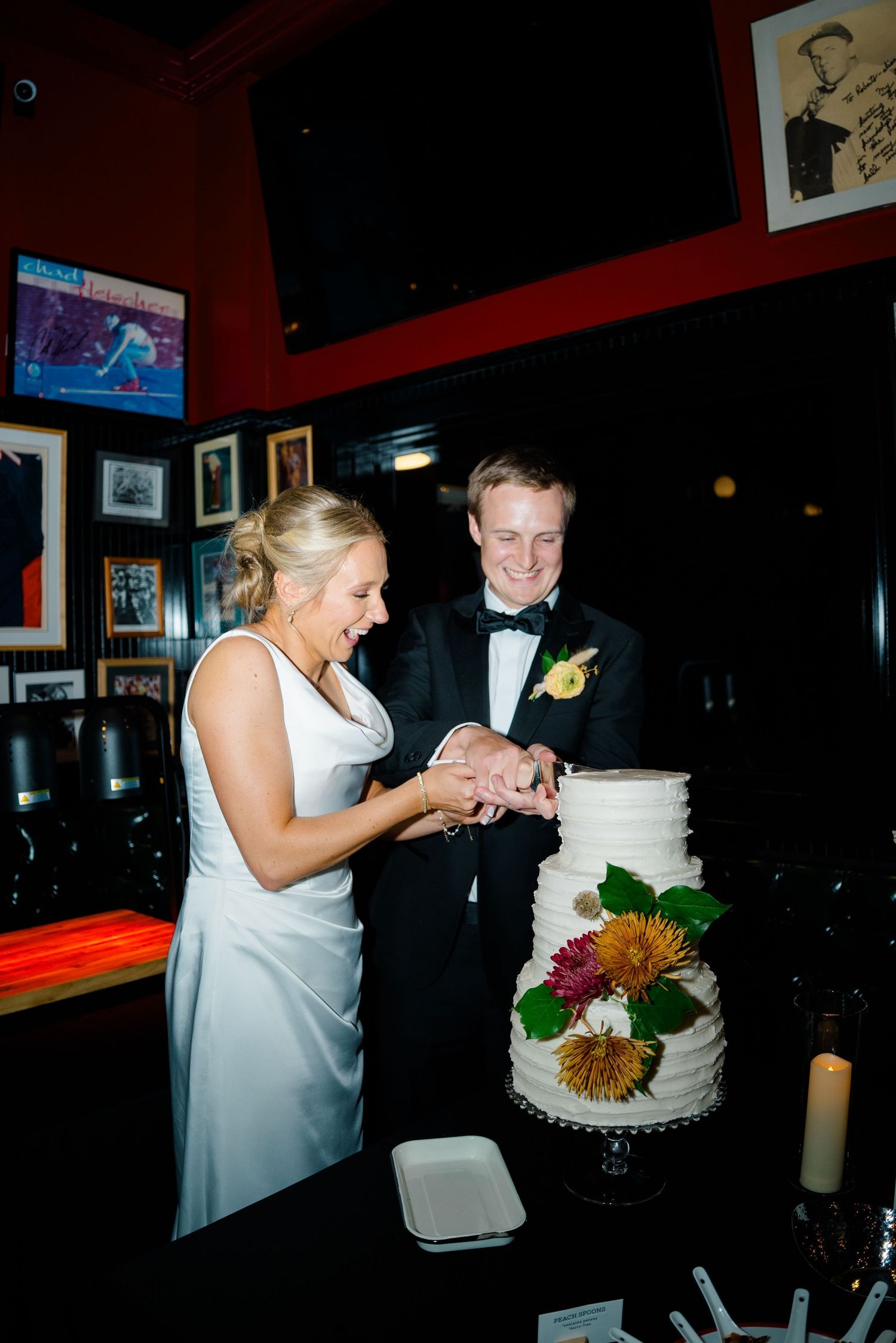Couple cuts their white wedding cake together at reception venue with dark interior in vail, colorado wedding.